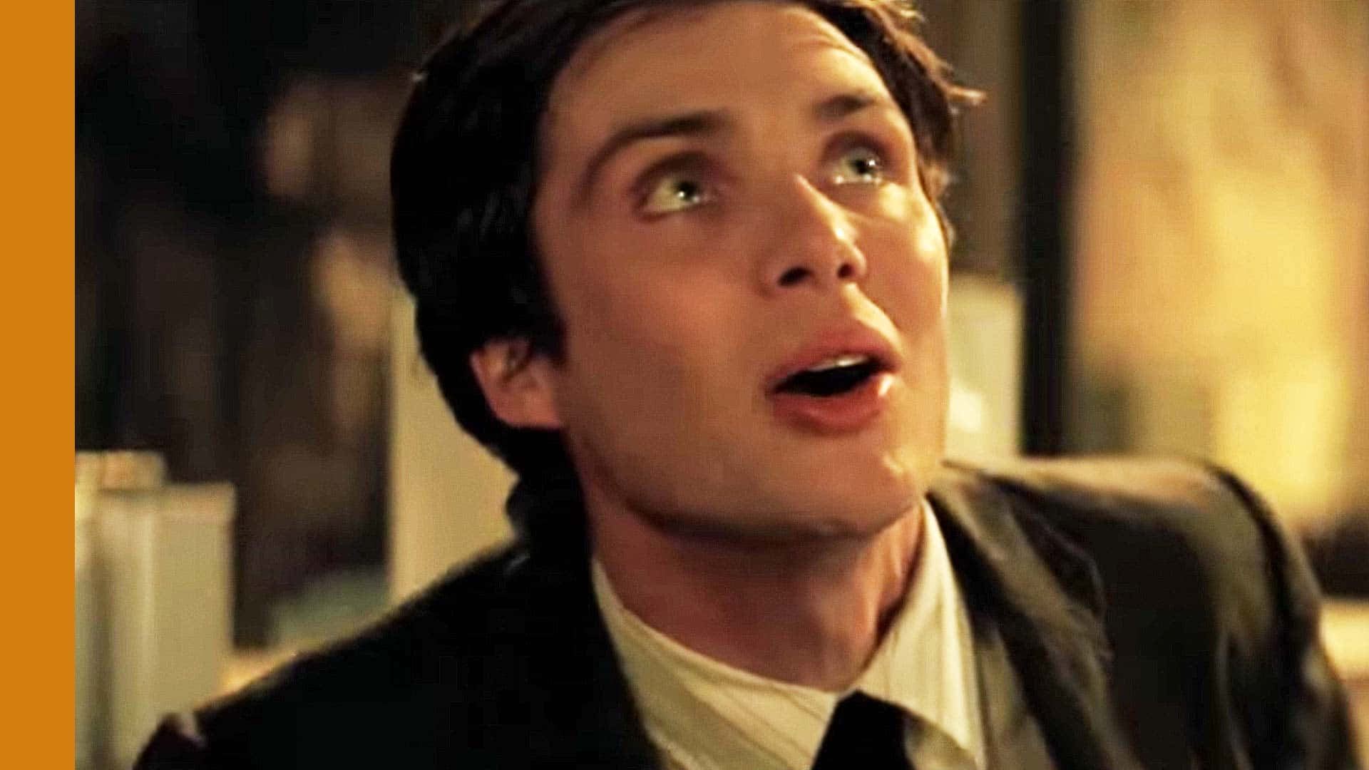 Batman Begins 桌布 壁紙 — 一名穿著西裝的男子在溫暖照明的室內場景中，睜大眼睛、張開嘴巴向上凝視。