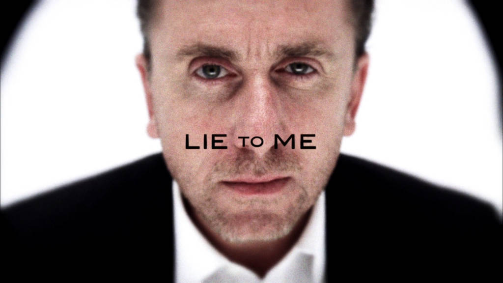 English 桌布 壁紙 — 一名穿著西裝的男子強烈地凝視著觀眾，臉上覆蓋著「LIE TO ME」的字樣。