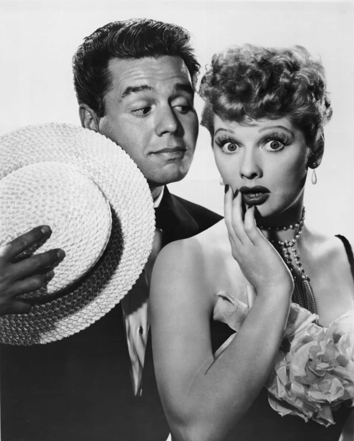 i love lucy 桌布 壁紙 — 一名穿著西裝的男子手持草帽，而一名捲髮女子露出震驚表情，手掩嘴巴，經典黑白工作室肖像。
