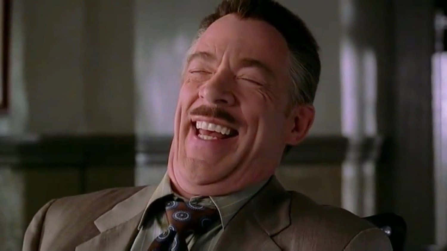 J Jonah Jameson 桌布 壁紙 — 一名穿著西裝的男子閉著眼睛，露出鬍鬚，開懷大笑。