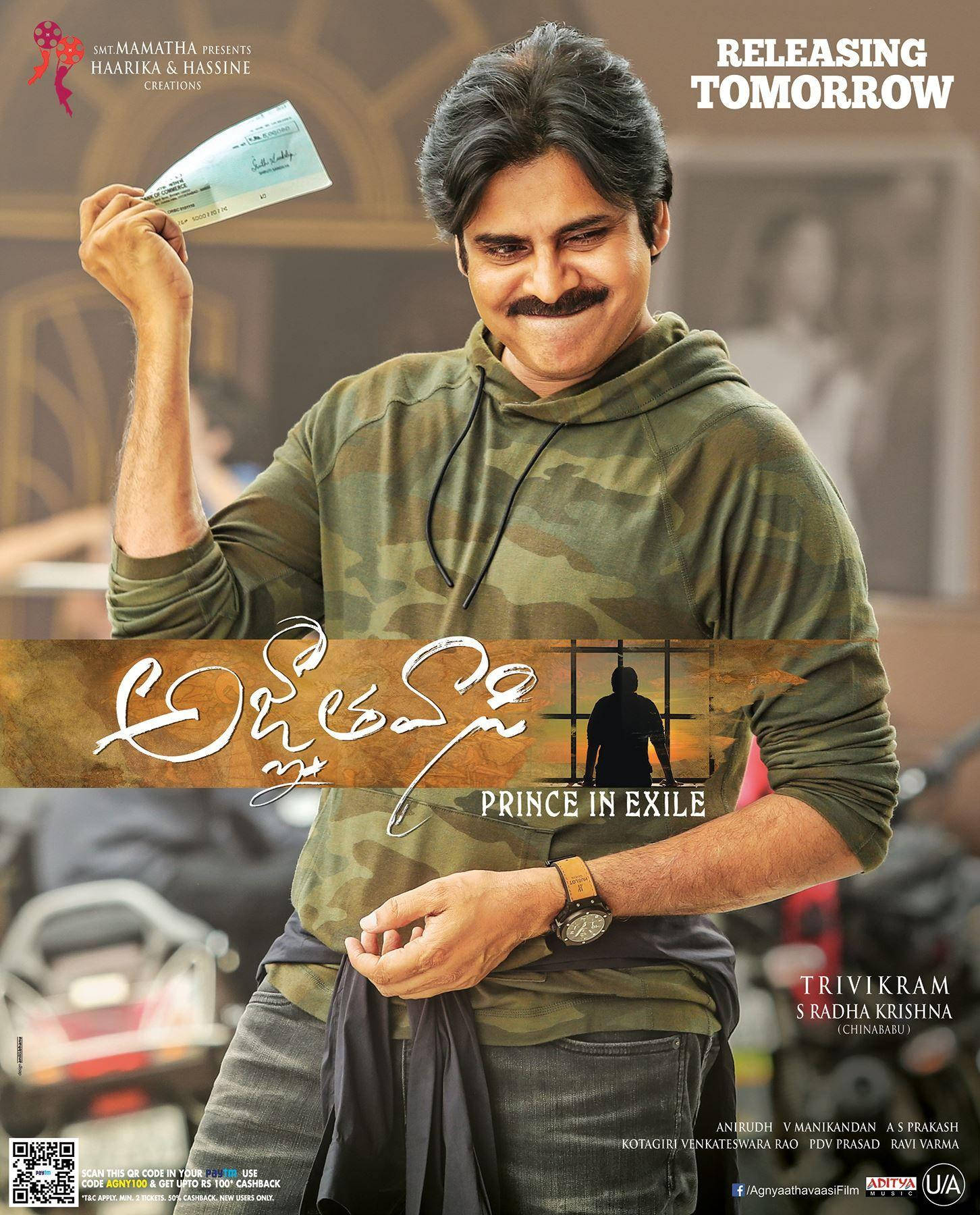 Pawan Kalyan 桌布 壁紙 — 一名穿著迷彩連帽衫的男子微笑著舉起一張門票，背景是模糊的城市景觀和電影字幕。