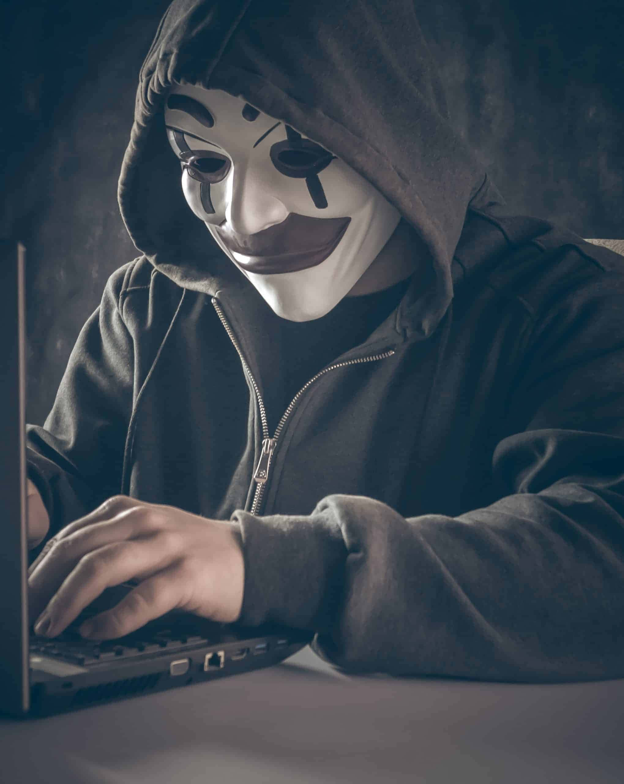 一名穿著連帽上衣的男子正在使用筆記型電腦 壁紙