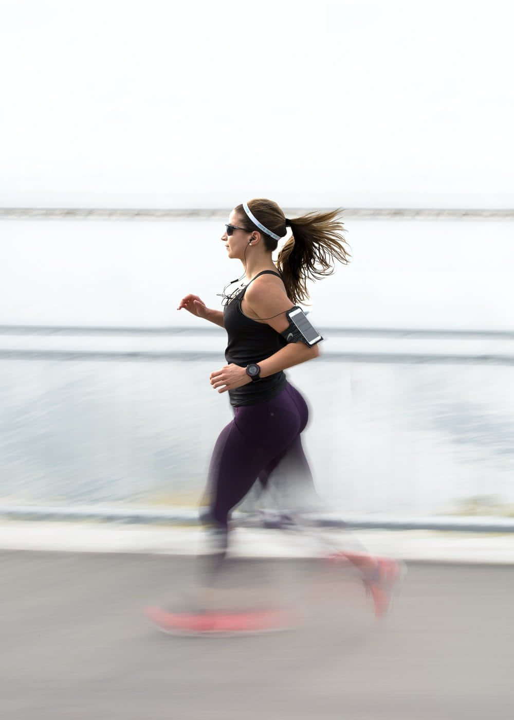 Workout 桌布 壁紙 — 一名穿著運動服的女性沿著海濱小徑奔跑，動態模糊捕捉了她充滿活力的動作。