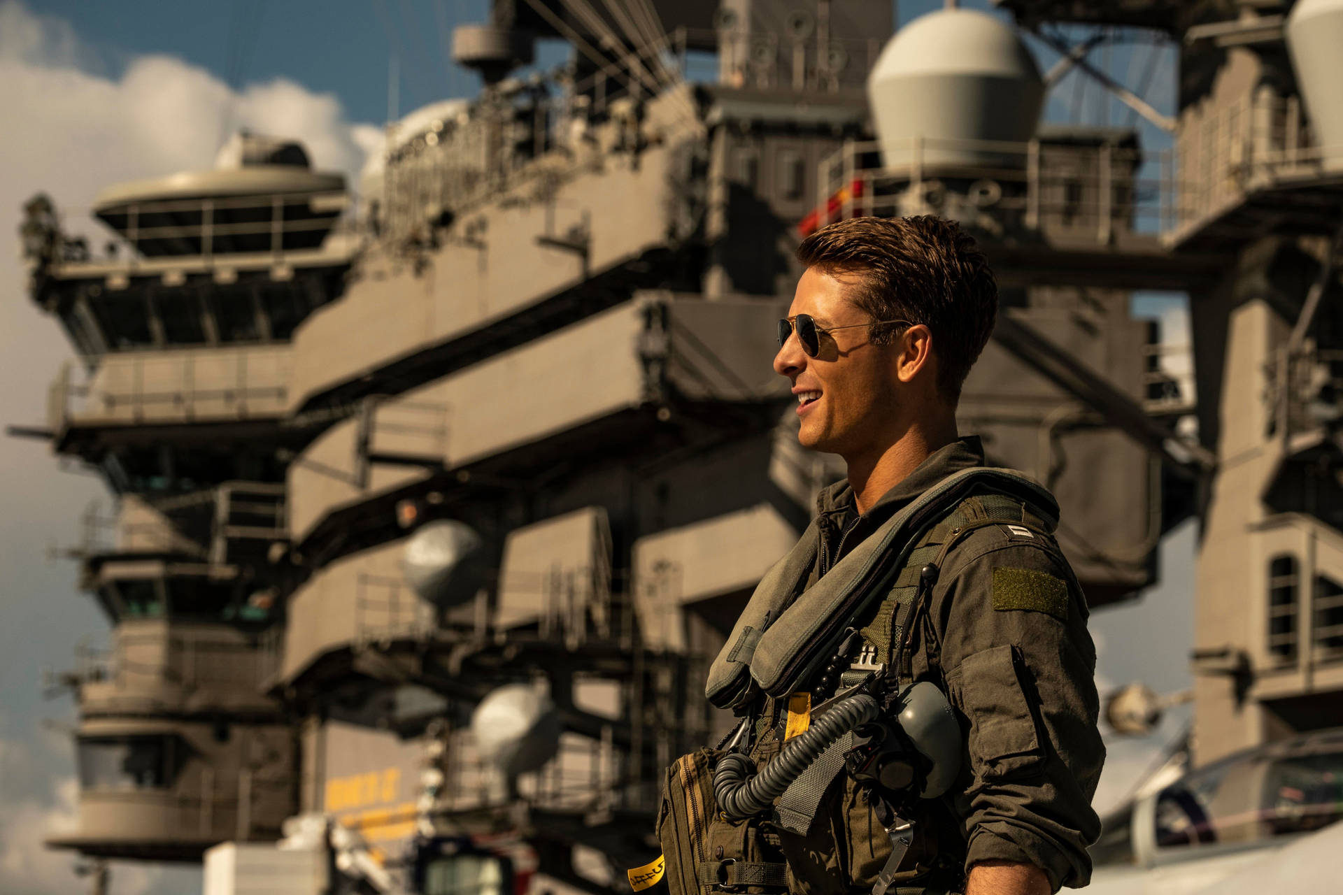 穿著飛行裝備的飛行員在航空母艦甲板上於日落時微笑。 — 捍衛戰士：獨行俠 壁紙