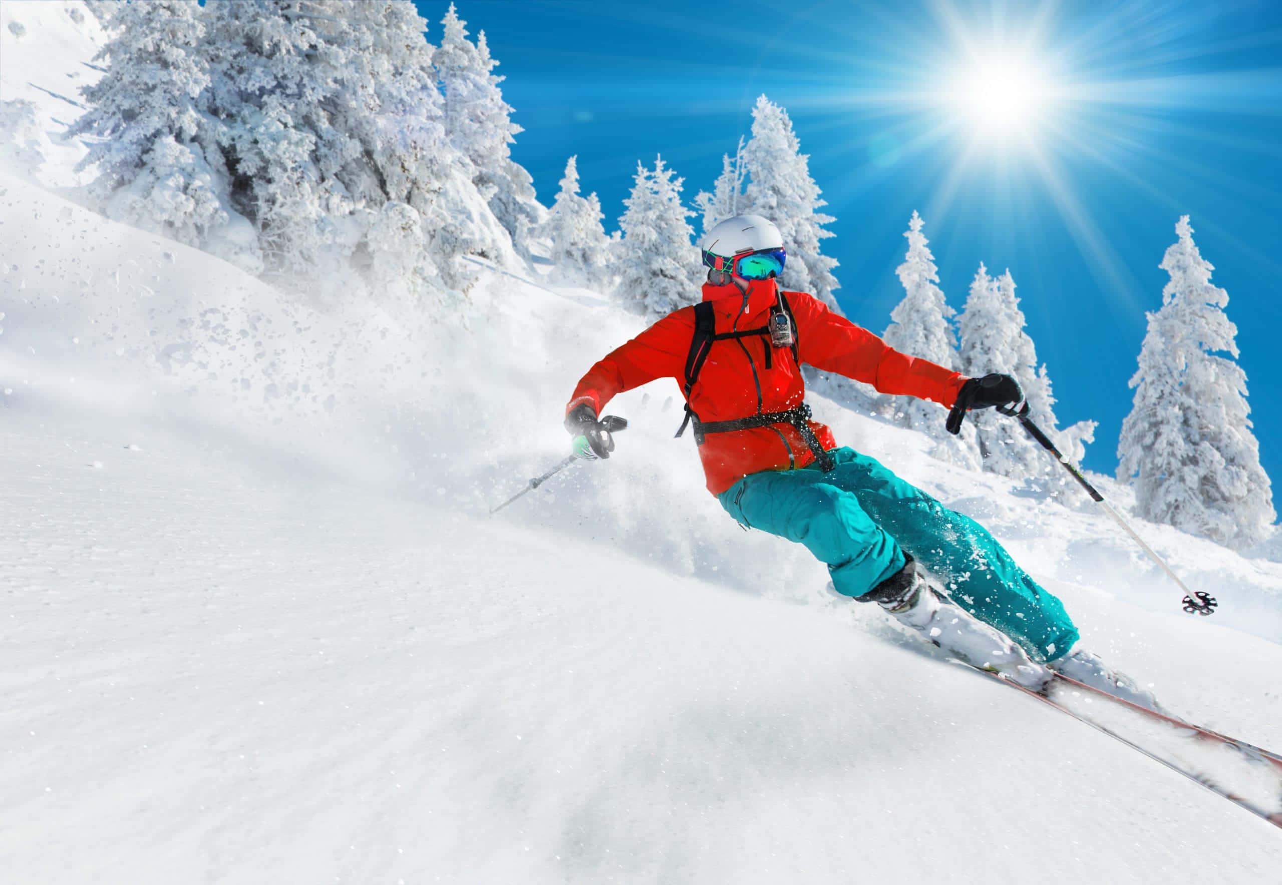 ski 桌布 壁紙 — 一名穿著鮮紅色外套和青綠色褲子的滑雪者，在熾熱的陽光下，在雪坡上劃過新鮮的粉雪。