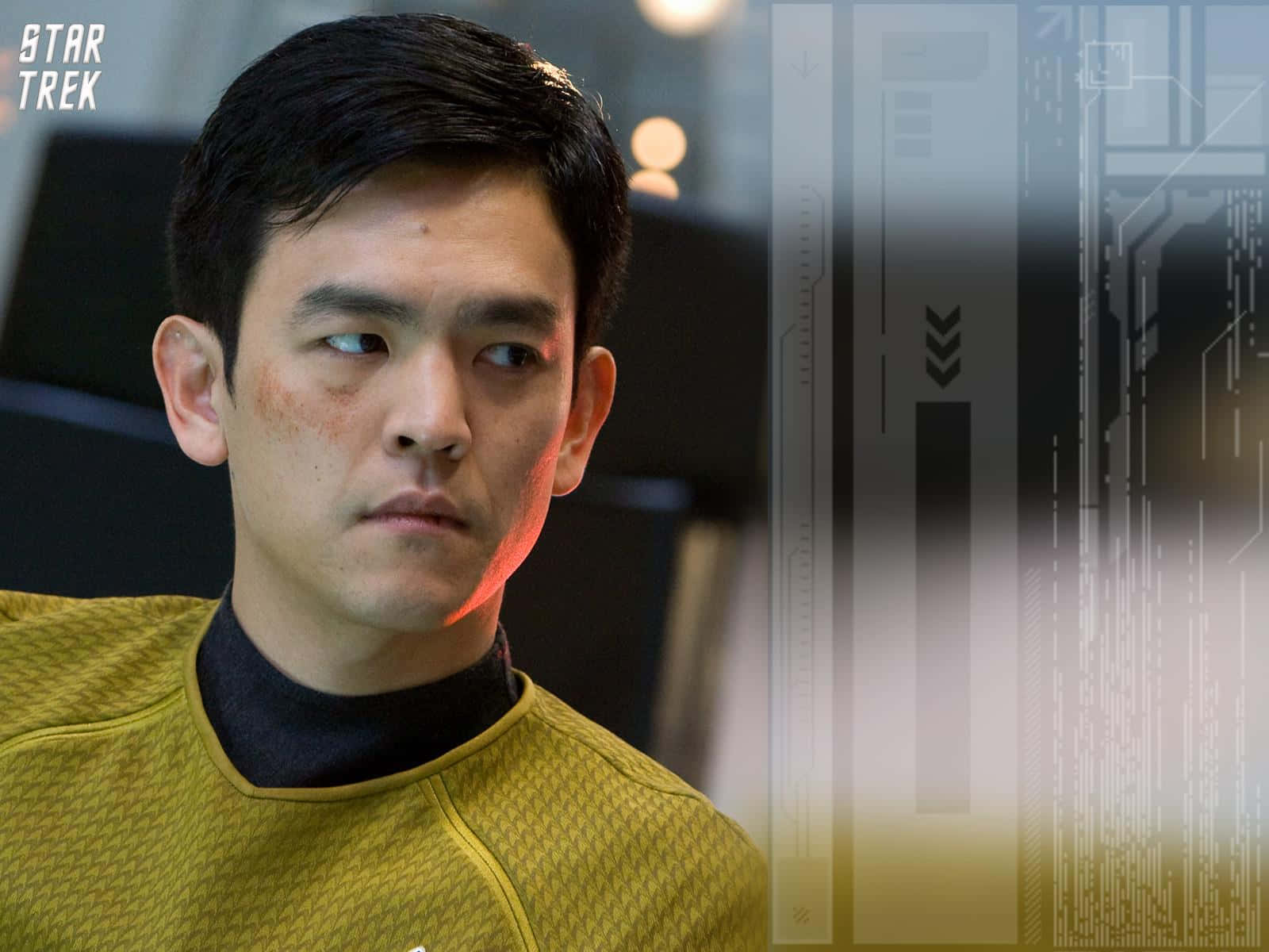 John Cho 桌布 壁紙 — 一名穿著黃色制服的星際爭霸戰軍官在未來感十足的太空船走廊中專注地看著鏡頭外。