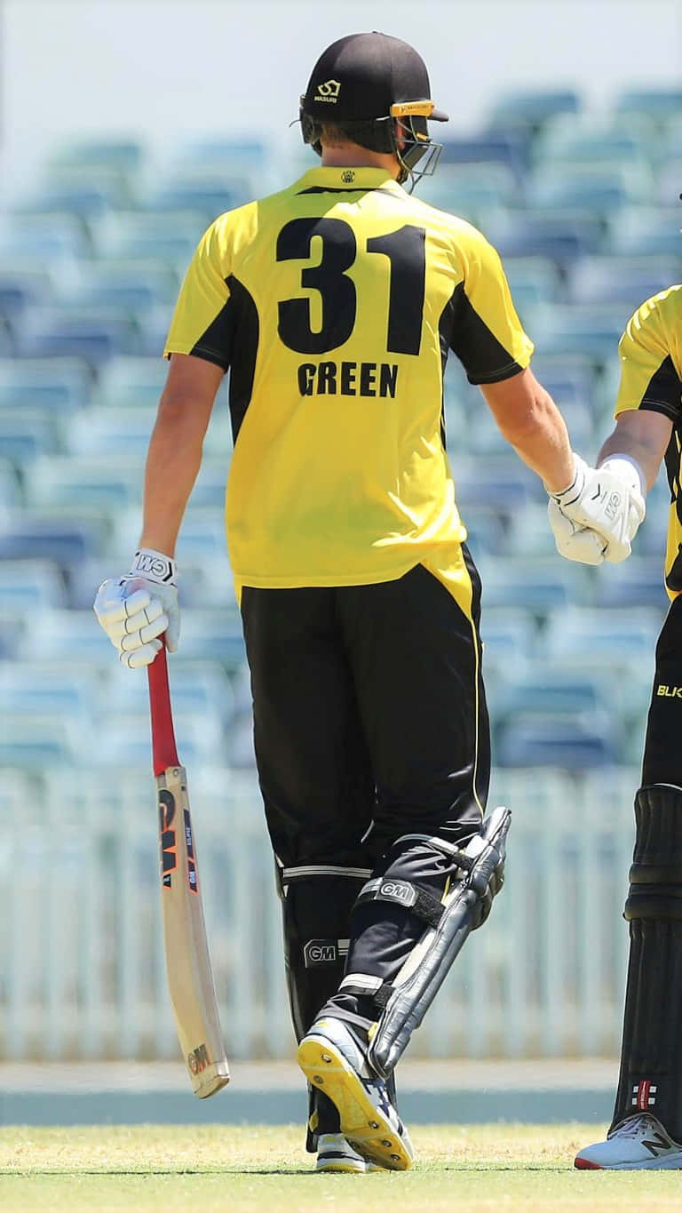 Cameron Green 桌布 壁紙 — 一名穿著黃黑相間制服、背號31的板球運動員手持球棒，在草地上背對鏡頭走開。
