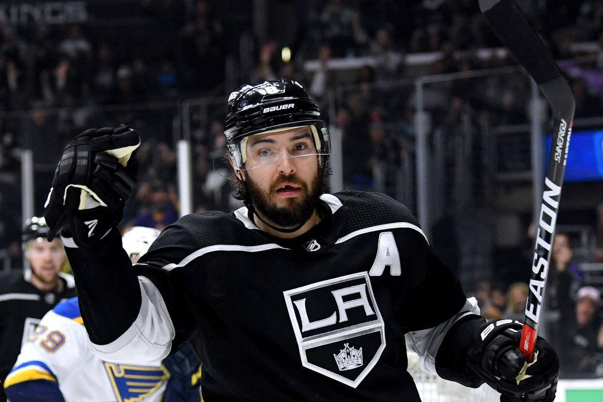 hockey 桌布 壁紙 — 一名穿著黑色LA Kings球衣的冰球運動員在明亮的場館燈光下進行激烈比賽時，舉起手套慶祝。