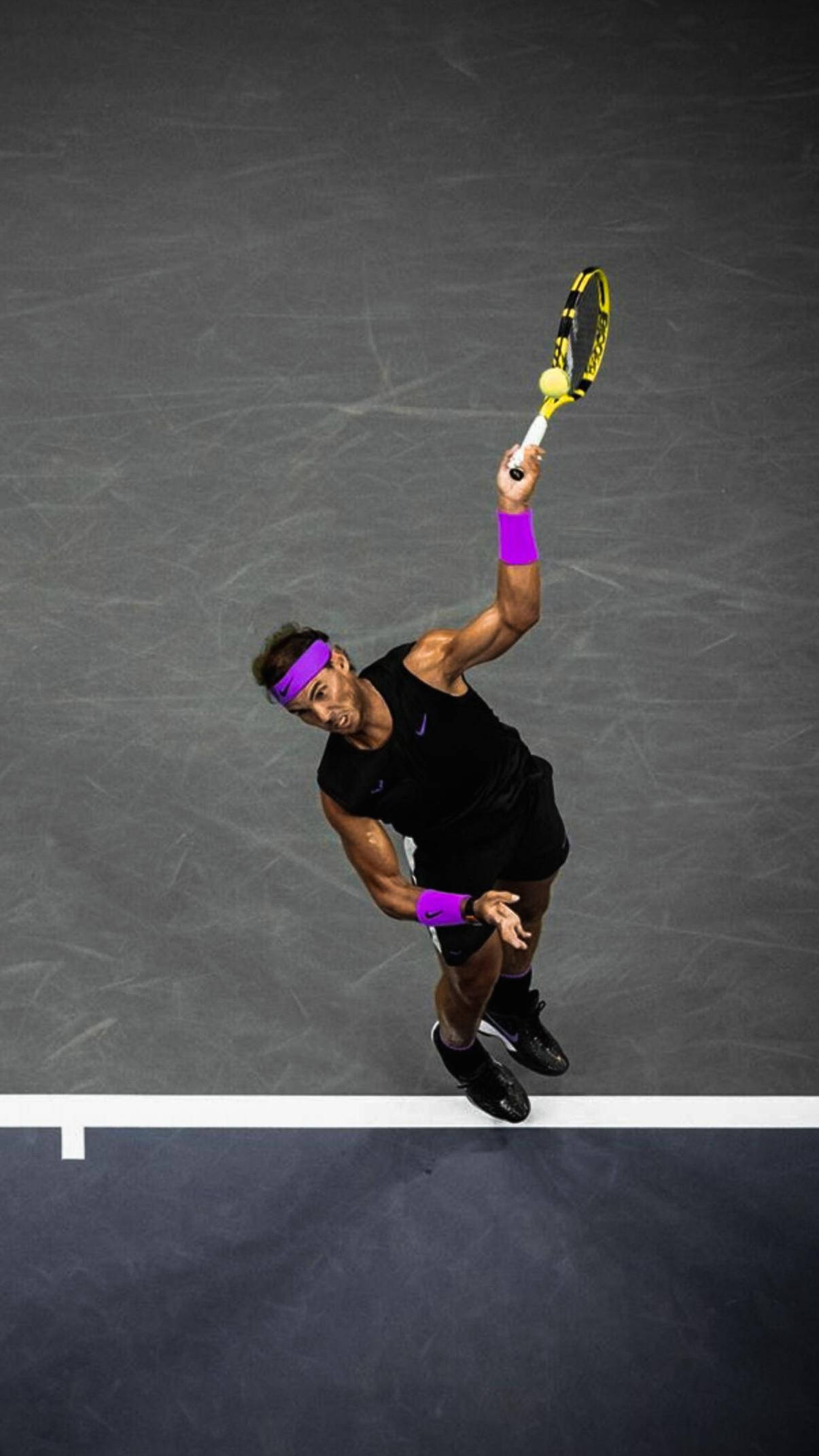 Tennis 桌布 壁紙 — 一名穿著黑色和紫色裝備的網球選手在明亮燈光下的黑暗球場上跳起正手擊球。