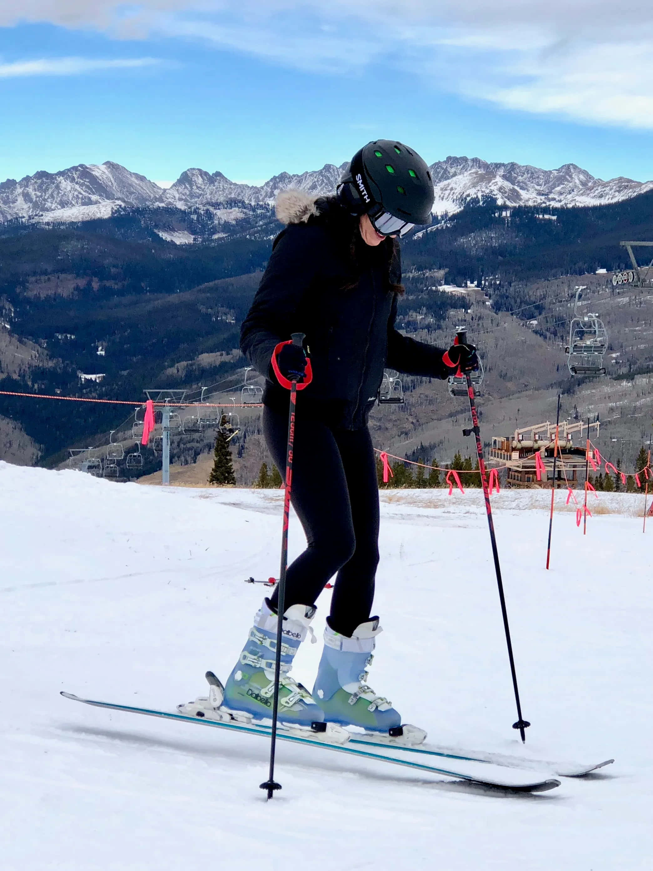 ski 桌布 壁紙 — 一名穿著黑色裝備的滑雪者，在晴朗的藍天下，以積雪的山脈和滑雪纜車為背景，沿著雪坡滑下。