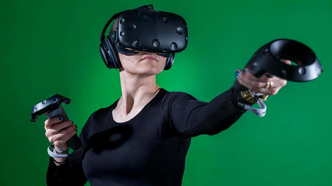 vr 桌布 壁紙 — 一名穿著黑色襯衫的人戴著VR頭戴式裝置，手持控制器，背景為純綠色螢幕。
