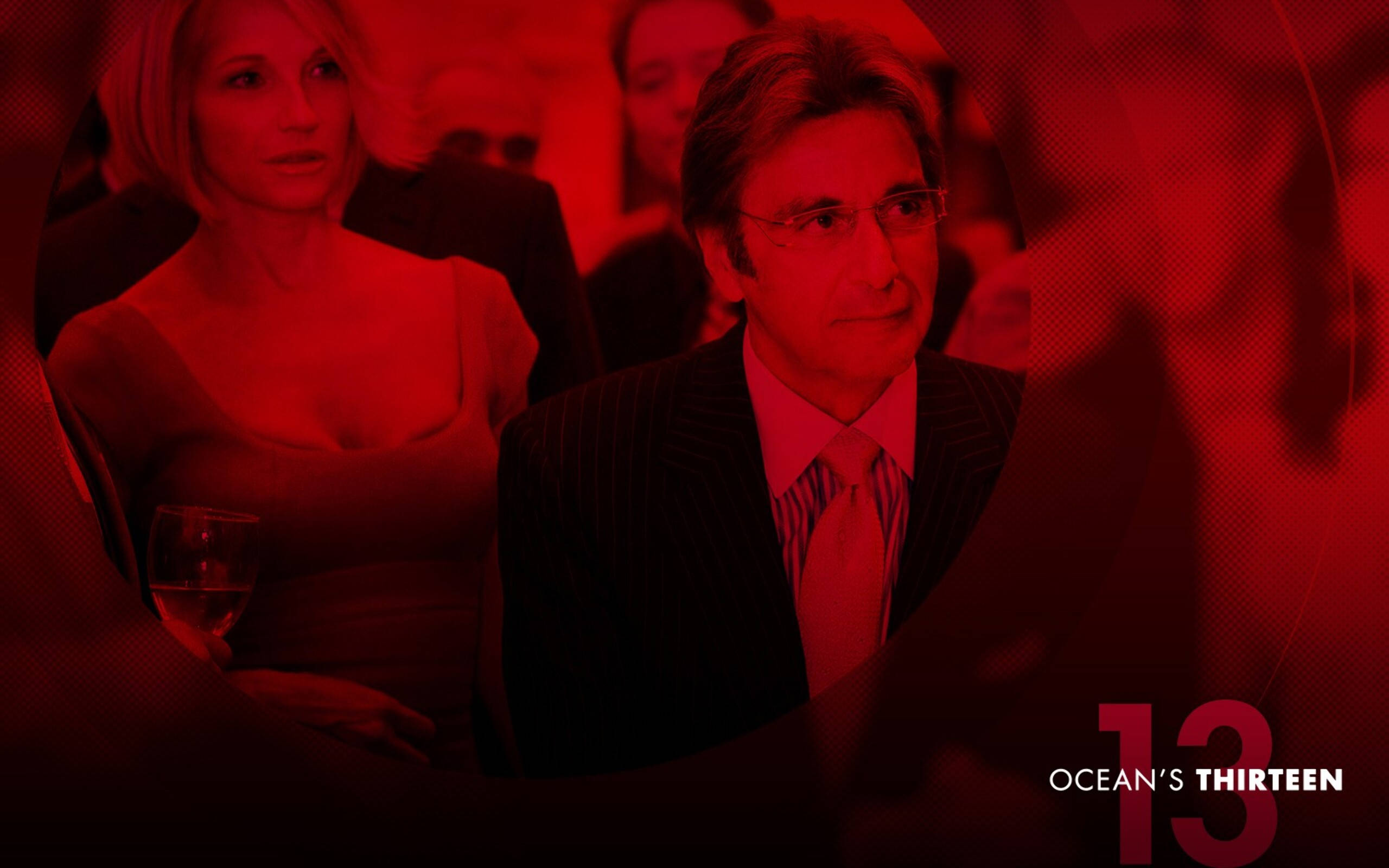 Al Pacino 桌布 壁紙 — 一名穿西裝的男子和一名穿連衣裙的女子坐在一個光線昏暗的房間裡，房間被強烈的紅光籠罩，並可見「Ocean's Thirteen」字樣。