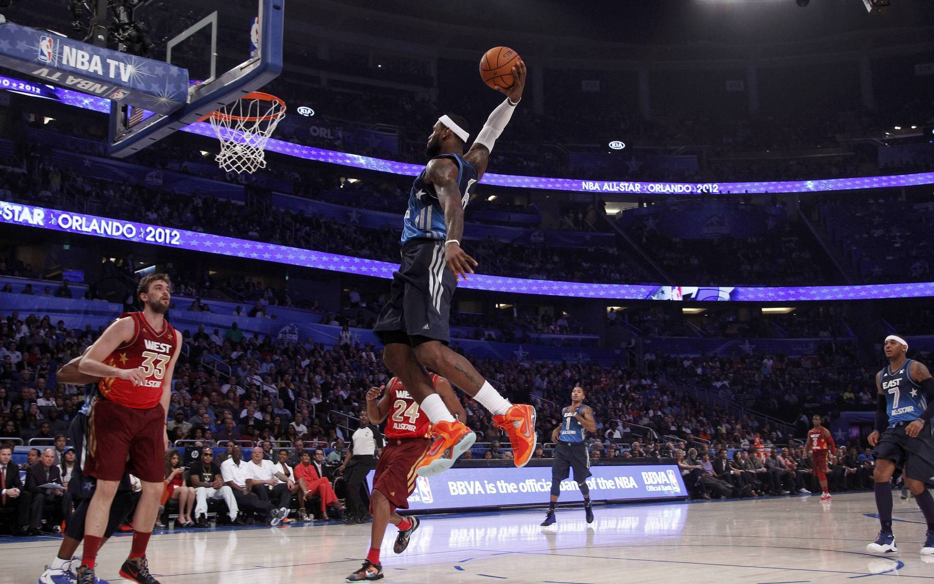 勒布朗·詹姆斯 桌布 壁紙 — 一名籃球運動員在NBA全明星賽中於空中灌籃，下方是座無虛席的場館。