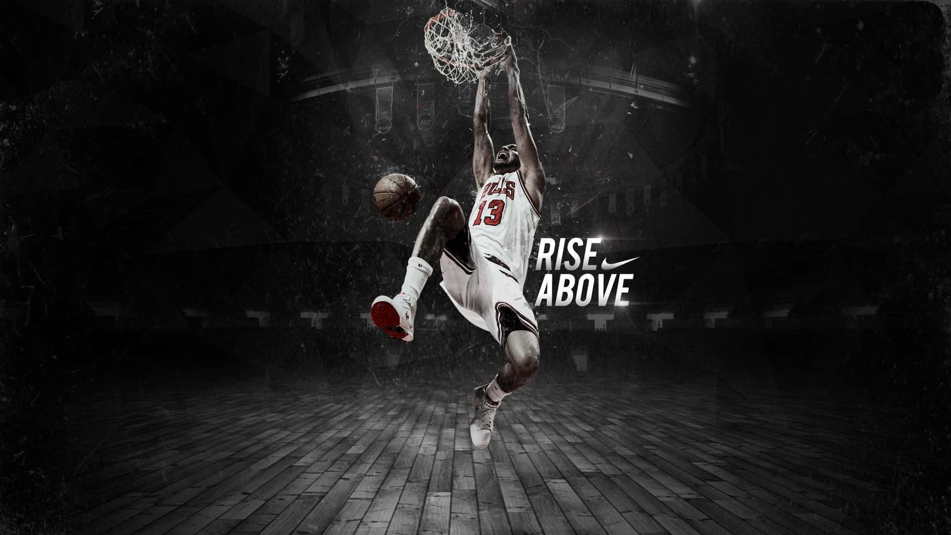 1080p Basketball 桌布 壁紙 — 一名籃球運動員在半空中灌籃，在昏暗的體育館中，旁邊有發光的「RISE ABOVE」文字。