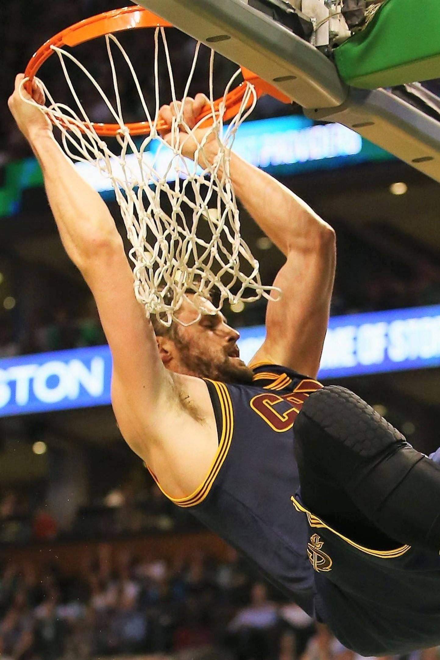 Kevin Love 桌布 壁紙 — 一名籃球運動員在燈光明亮的場館中完成強力灌籃後，倒掛在籃框上。