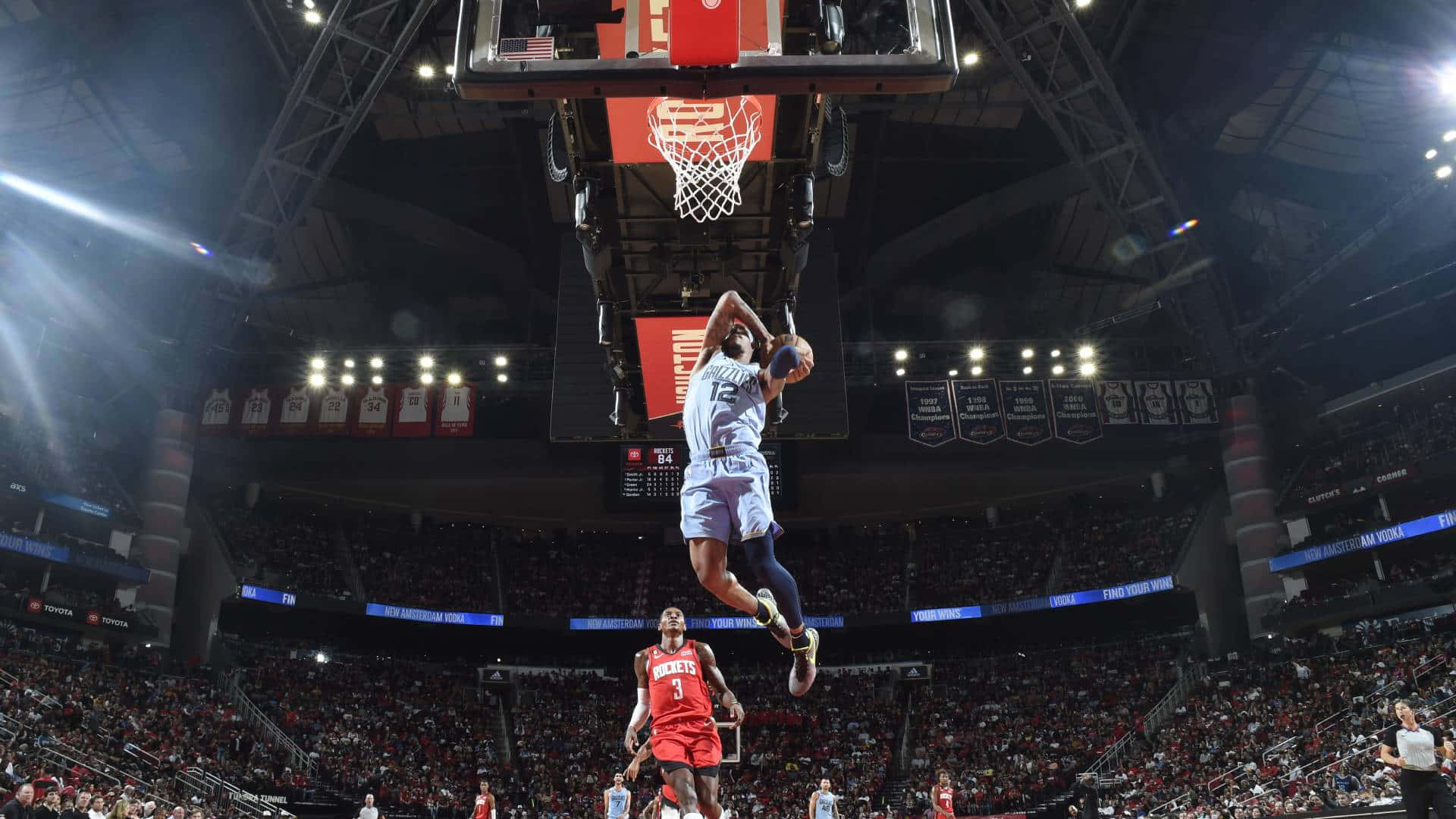 Ja Morant 動圖 桌布 壁紙 — 一名籃球運動員在空中飛翔，準備大力灌籃，下方燈火通明的場館內觀眾歡呼雷動。