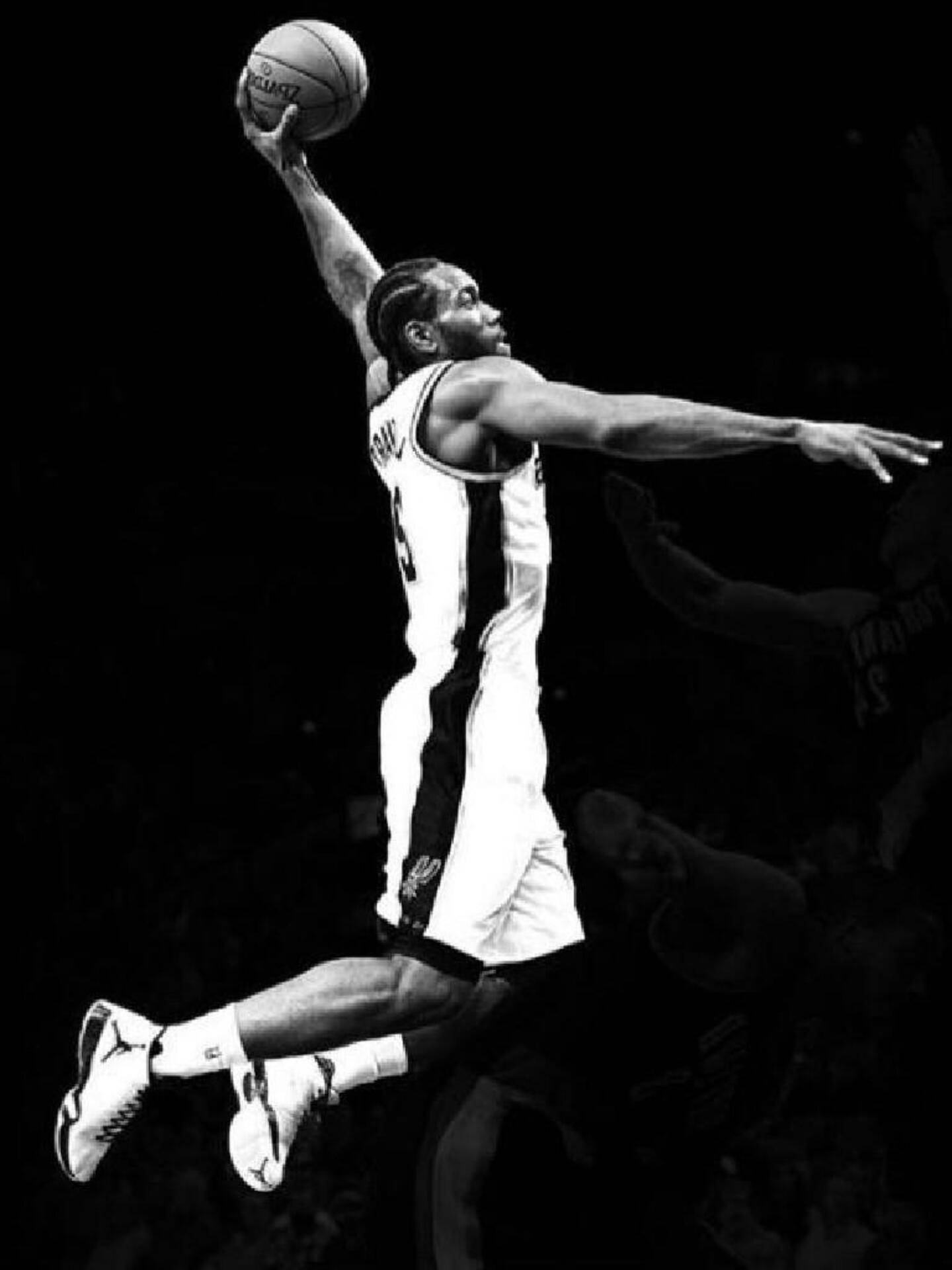 Kawhi 桌布 壁紙 — 一名籃球運動員在黑白畫面中高高躍起，在空中以強烈專注力將球灌入籃框，背景為深色。