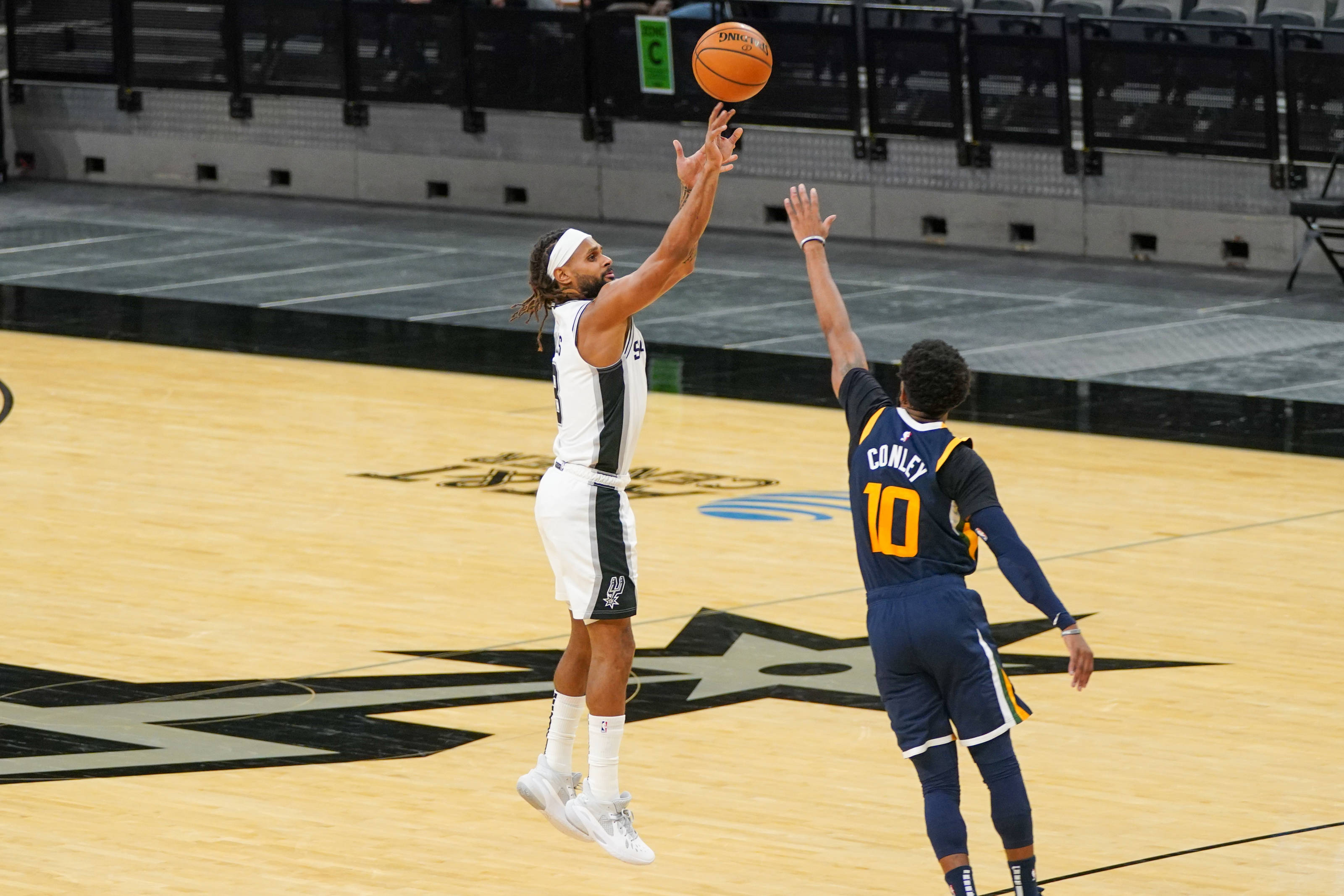 mike conley 桌布 壁紙 — 一名籃球運動員跳起投籃，而一名防守球員跳起封阻，在室內場館中。