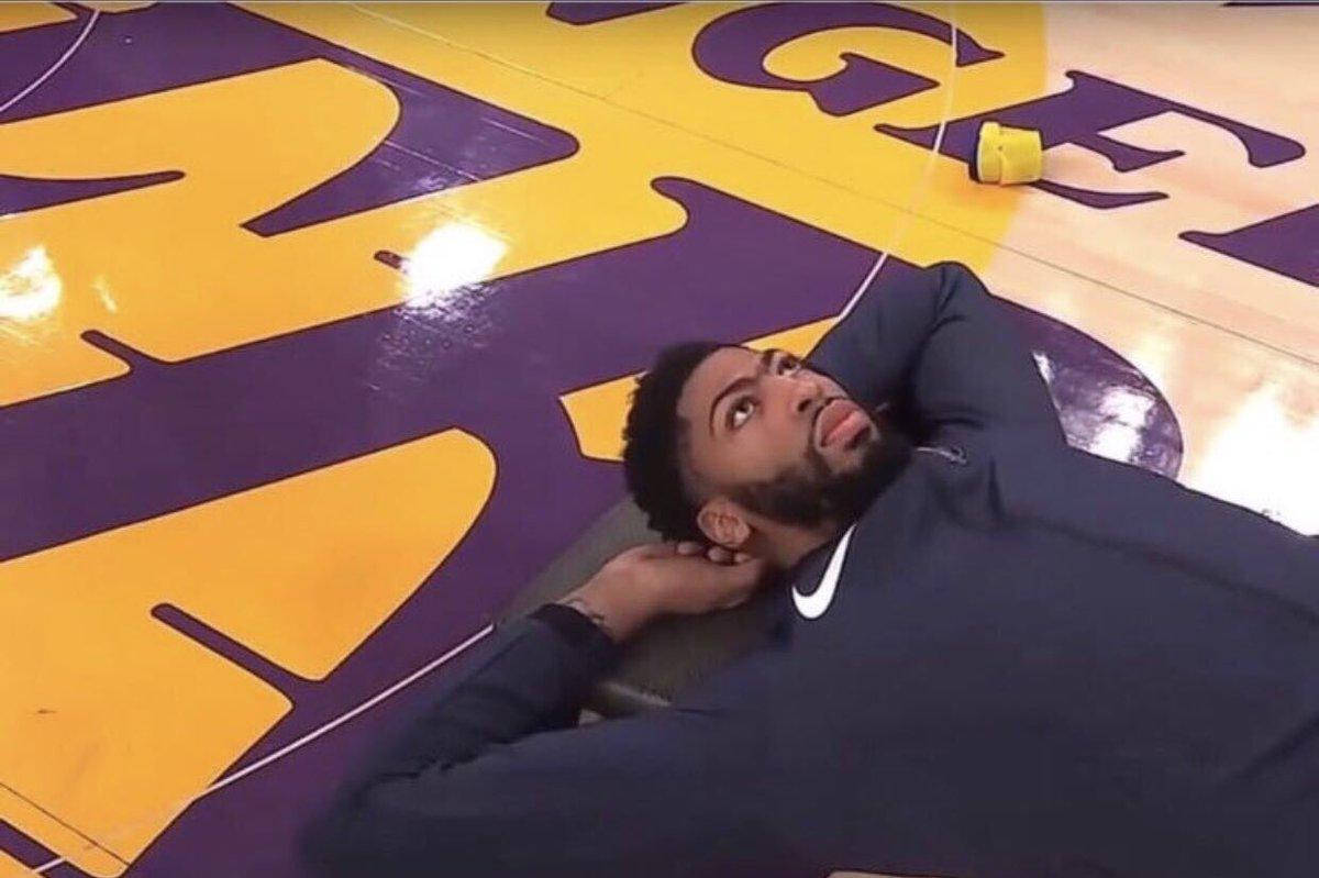 Anthony Davis 桌布 壁紙 — 一名籃球運動員躺在湖人隊球場地板上，抬頭仰望，表情沉思。