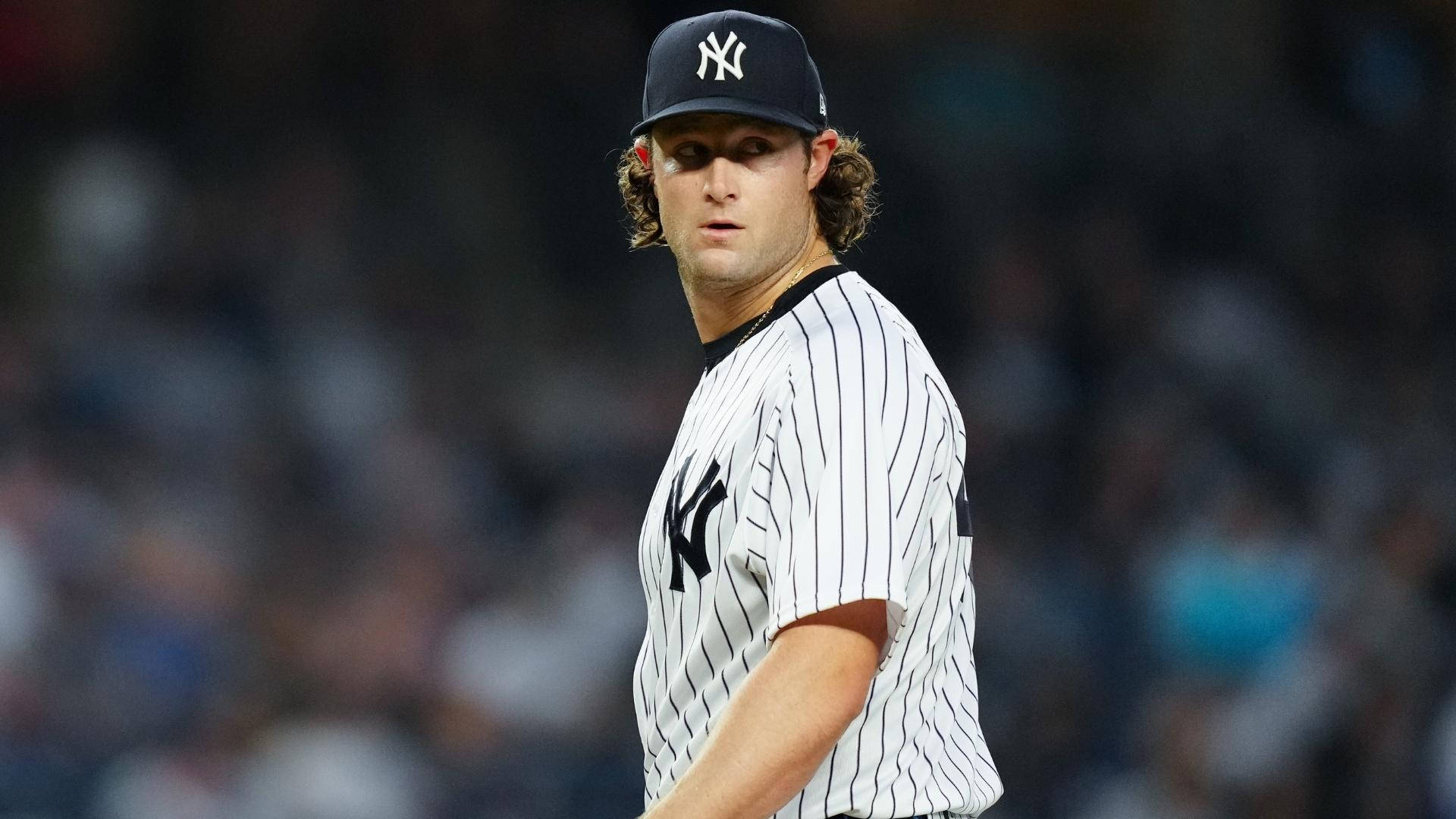 Gerrit Cole 桌布 壁紙 — 一名紐約洋基隊棒球選手身穿細條紋球衣，在球場燈光下專注地站在場上。