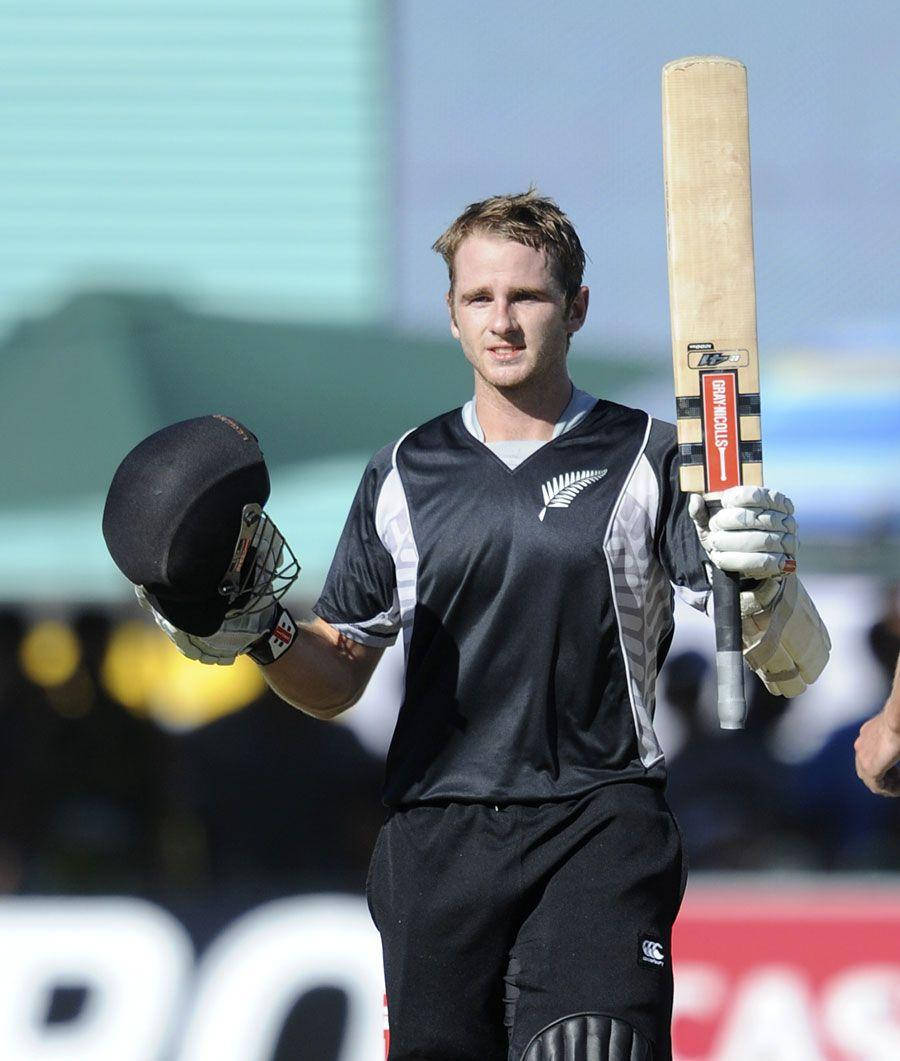 kane williamson 桌布 壁紙 — 一名紐西蘭板球運動員身穿黑色制服，手持球棒和頭盔，在陽光明媚的場地上行走。
