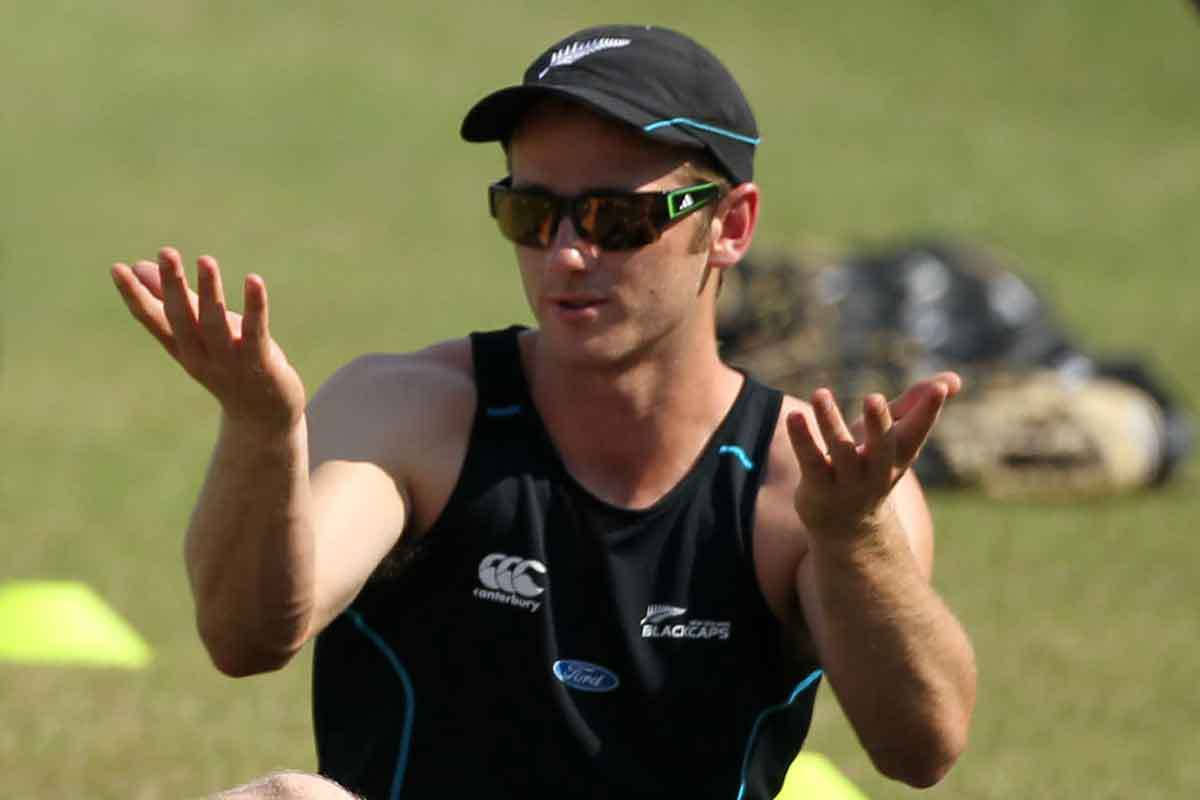 kane williamson 桌布 壁紙 — 一名紐西蘭板球運動員身穿黑色訓練球衣和帽子，在陽光明媚的草地上生動地做手勢。