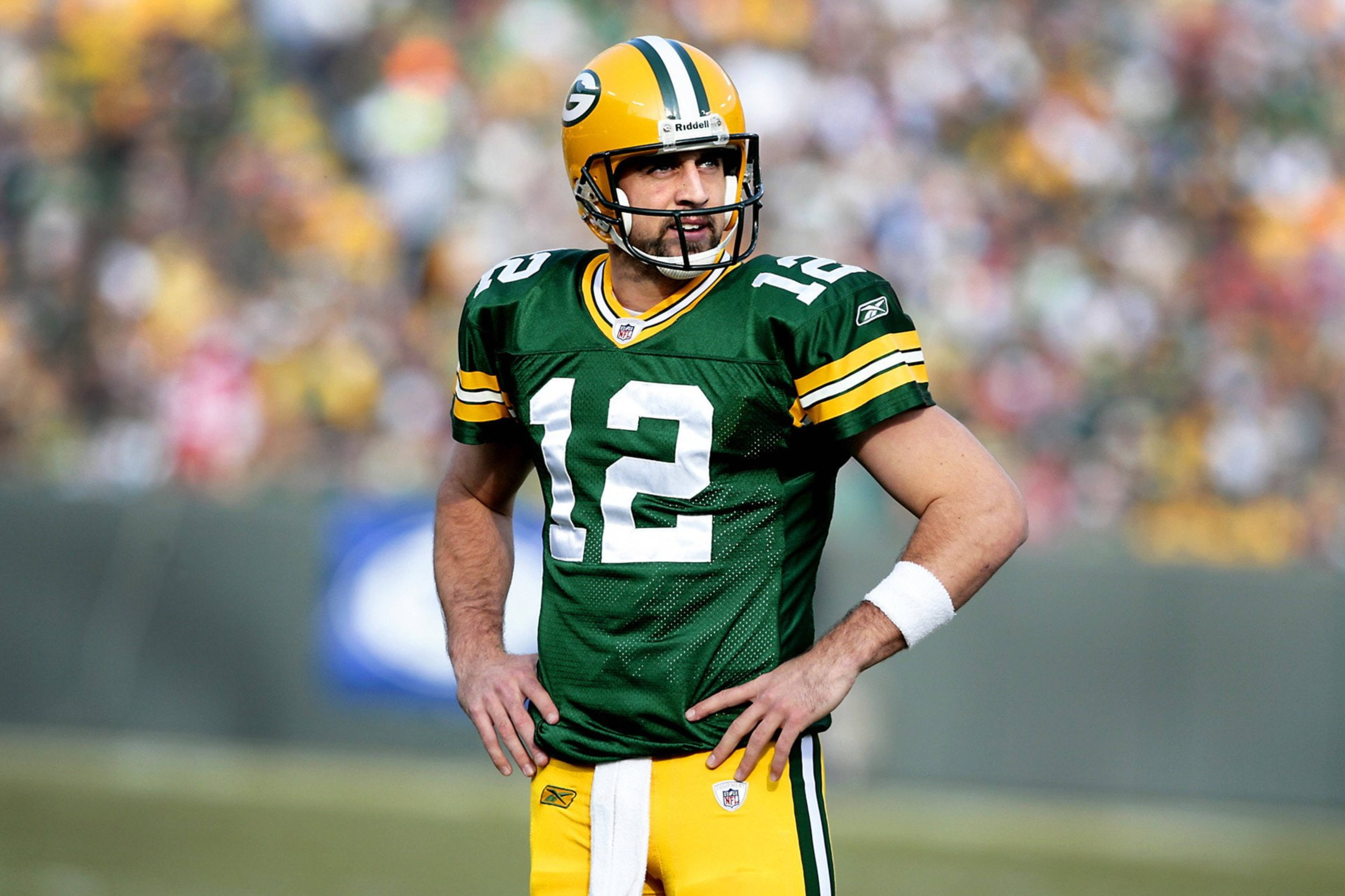 Aaron Rodgers 桌布 壁紙 — 一名綠灣包裝工的四分衛穿著綠色和金色球衣，在比賽中雙手叉腰站在球場上。