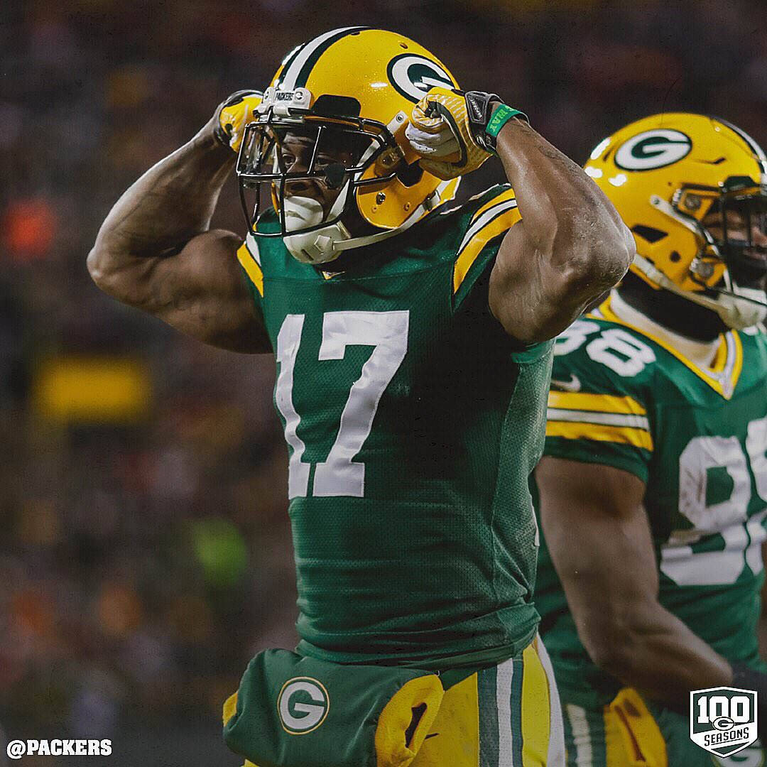 Davante Adams 桌布 壁紙 — 一名綠灣包裝工美式足球員身穿綠色和金色球衣，在夜間比賽中於球場燈光下高舉雙臂慶祝。