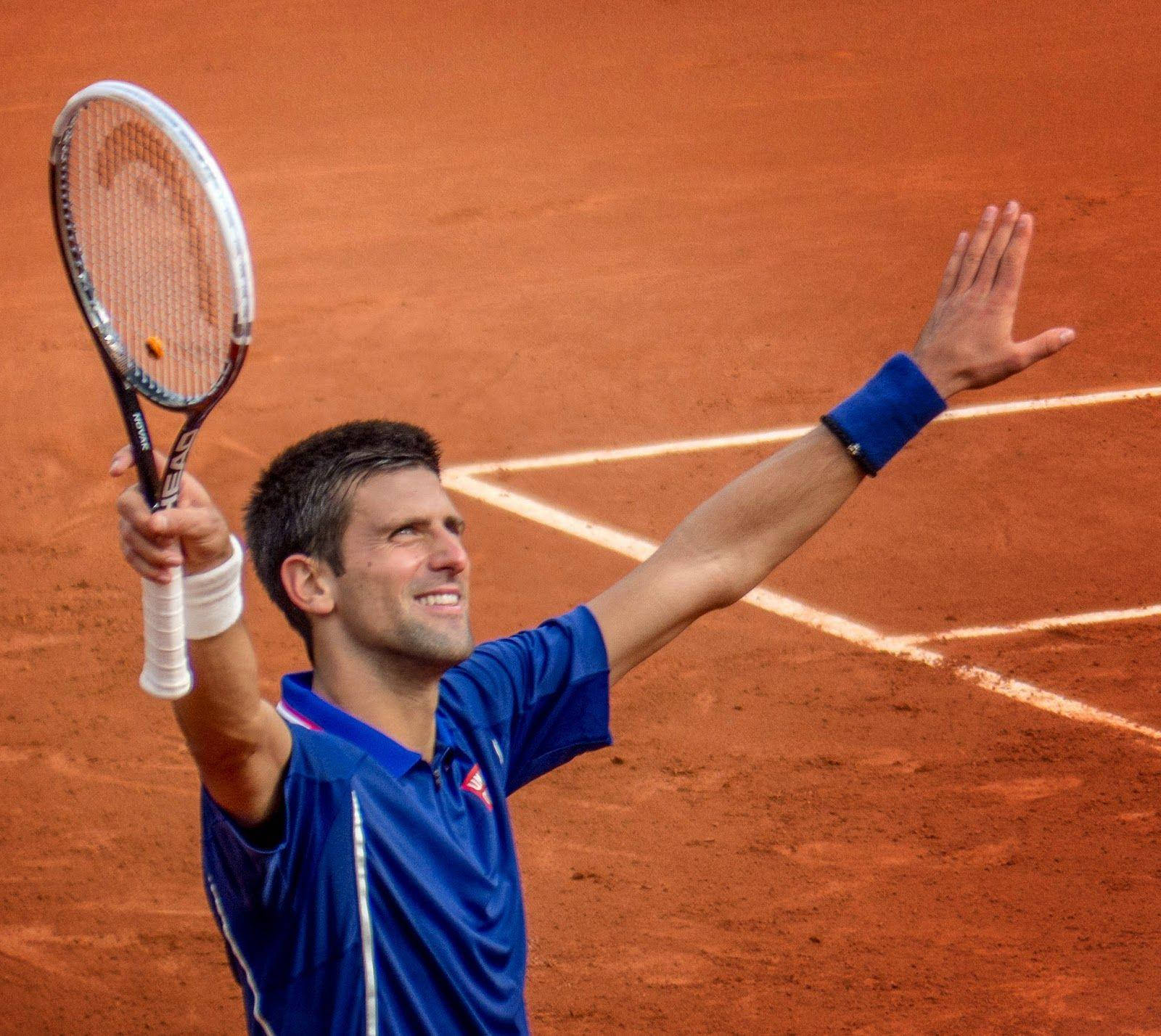 french 桌布 壁紙 — 一名網球運動員在紅土場上高舉球拍、張開雙臂慶祝勝利。