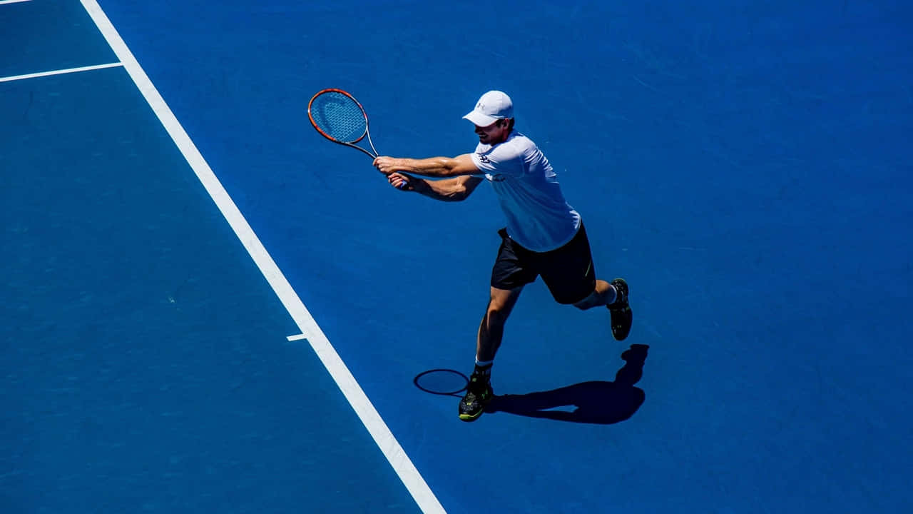 720p Tennis 桌布 壁紙 — 一名網球運動員在鮮豔的藍色球場上揮拍，明亮的日光下投射出清晰的陰影。