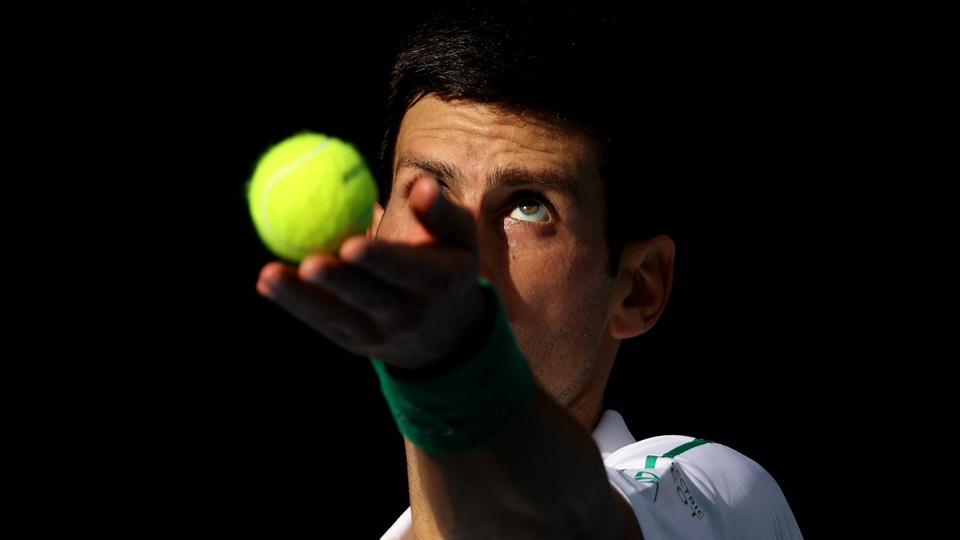 Novak 桌布 壁紙 — 一名網球運動員在黑色背景下專注於一個亮黃色的球。