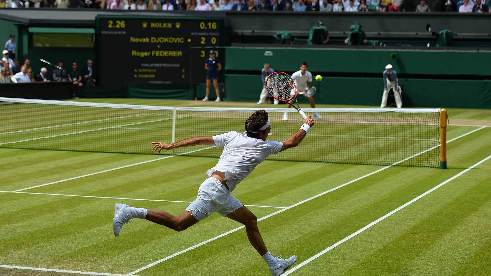Wimbledon 桌布 壁紙 — 一名網球選手在草地場上向前撲出正手擊球，比賽中有觀眾和記分板可見。