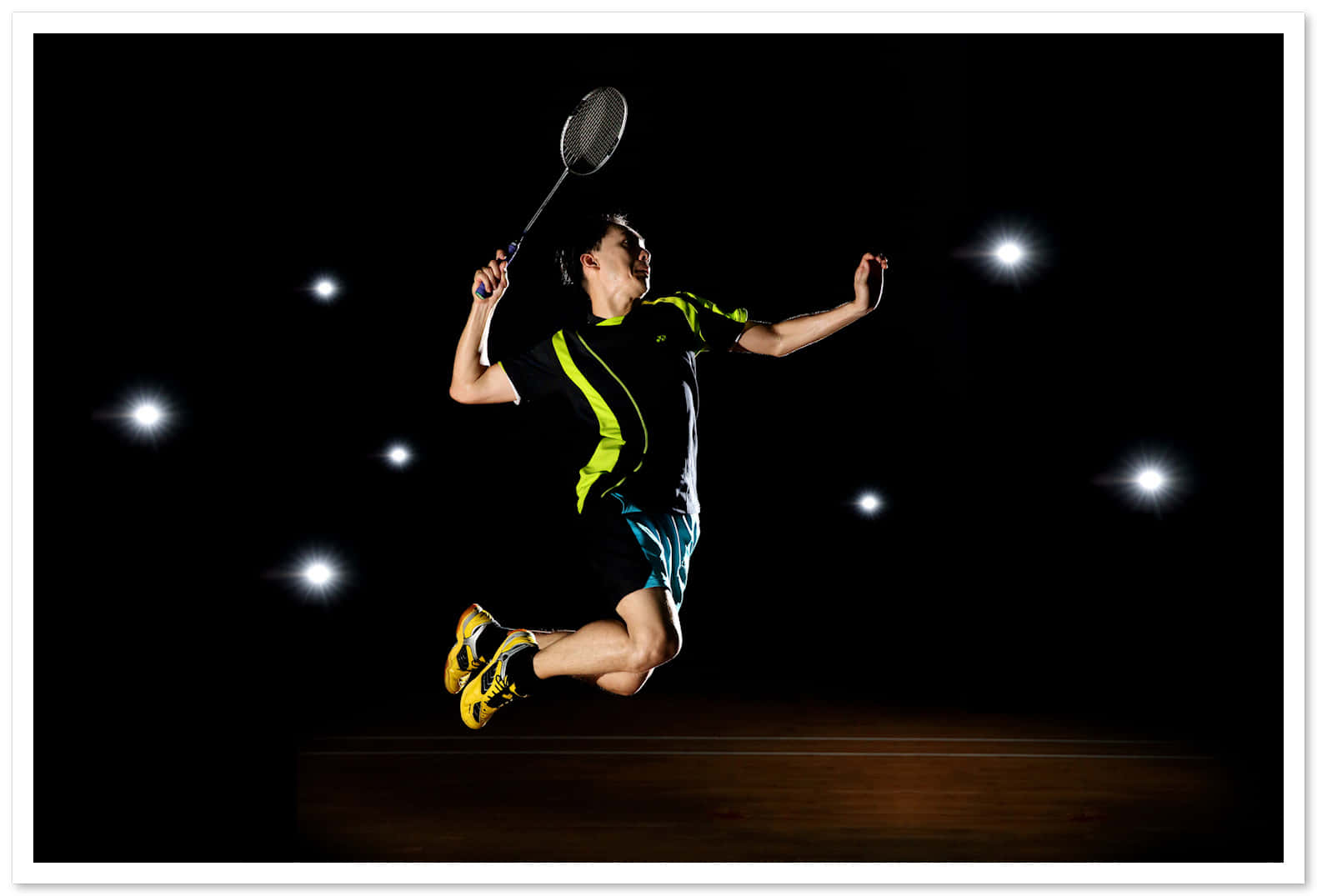 HD Badminton 桌布 壁紙 — 一名羽球運動員在黑暗背景下被明亮的聚光燈照亮，手持球拍躍起空中。