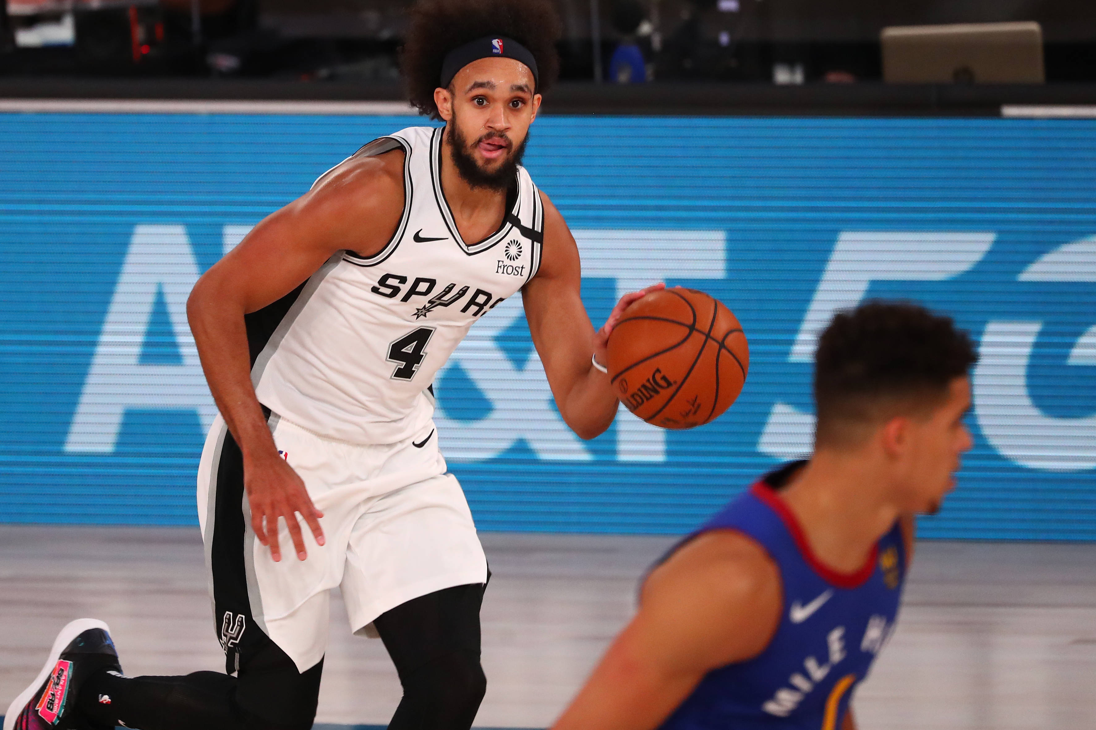 NBA 桌布 壁紙 — 一名聖安東尼奧馬刺籃球運動員在燈光明亮的場館中運球，同時被防守。