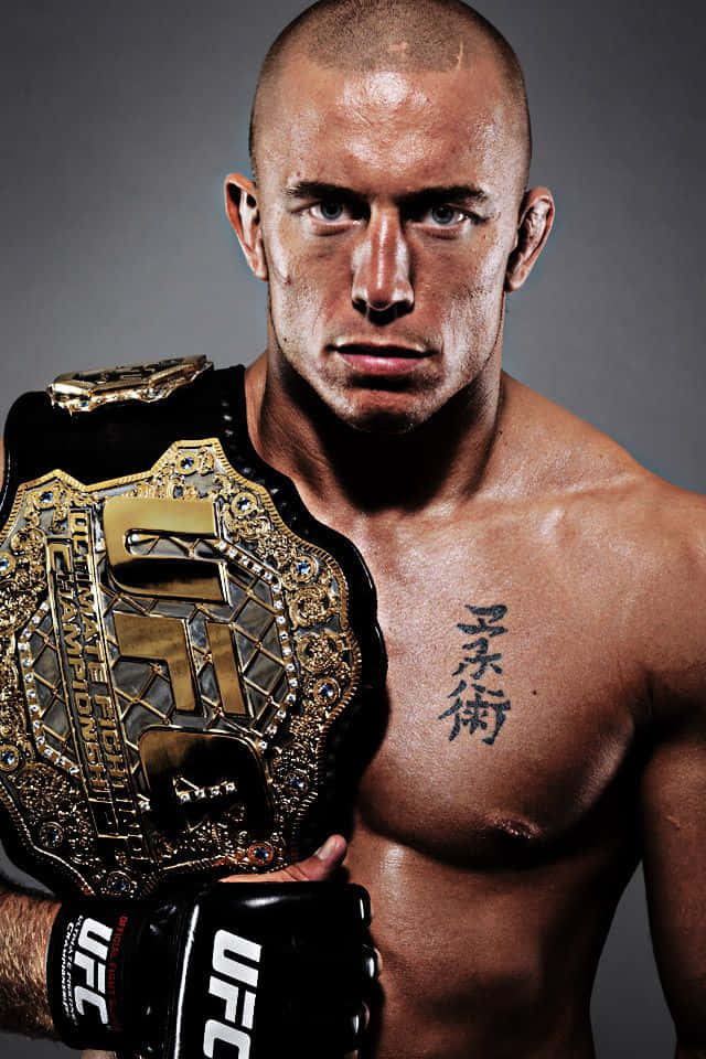 martial arts 桌布 壁紙 — 一名肌肉發達、剃光頭的UFC拳手在灰色工作室背景下，手持冠軍腰帶，眼神銳利。