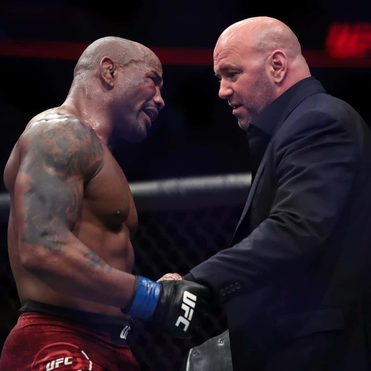 martial arts 桌布 壁紙 — 一名肌肉發達、有紋身的拳手穿著紅色短褲，在UFC八角籠內與一名身穿黑色西裝的光頭男子握手。