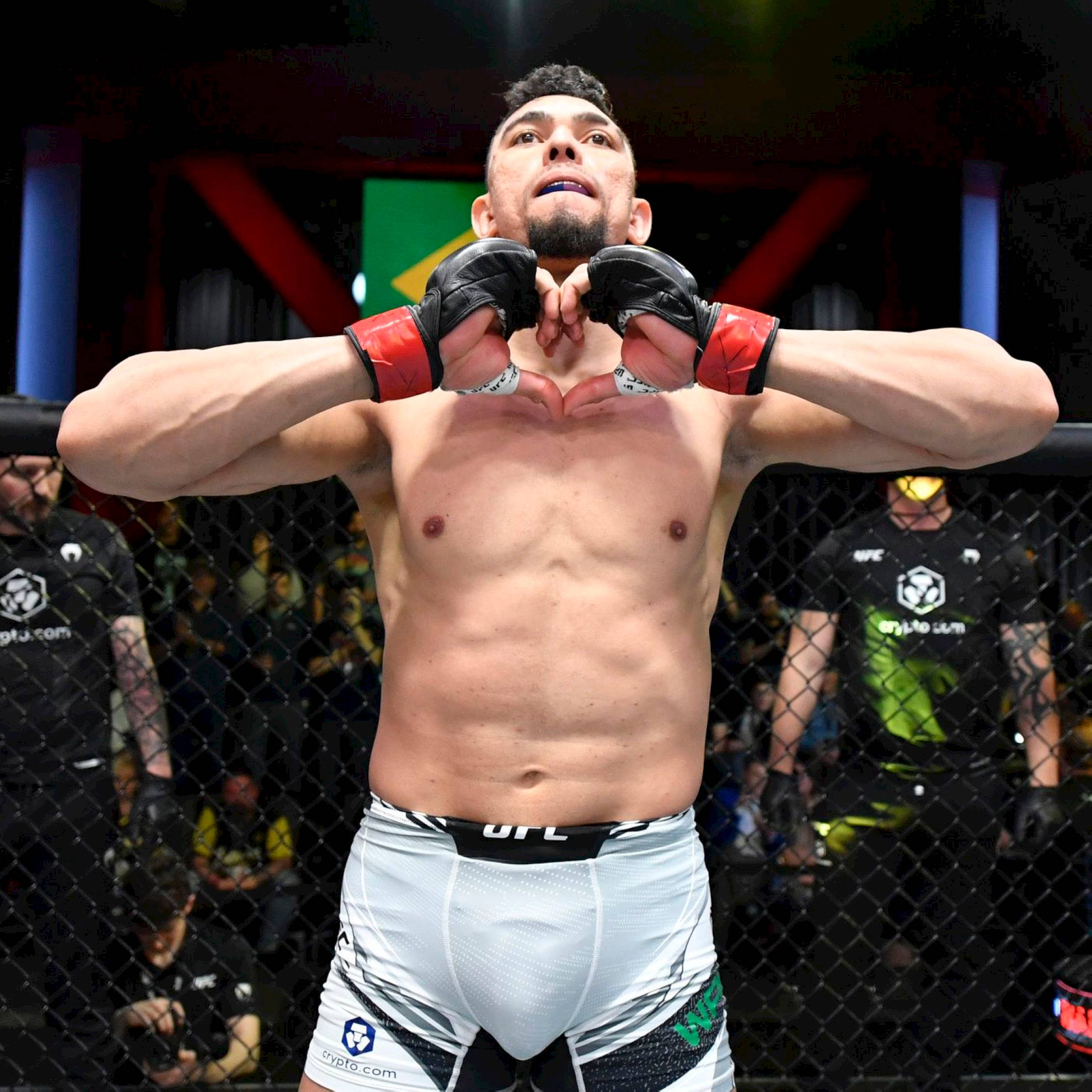 MMA 桌布 壁紙 — 一名肌肉發達的UFC拳手在八角籠內用戴著手套的雙手做出心形手勢。