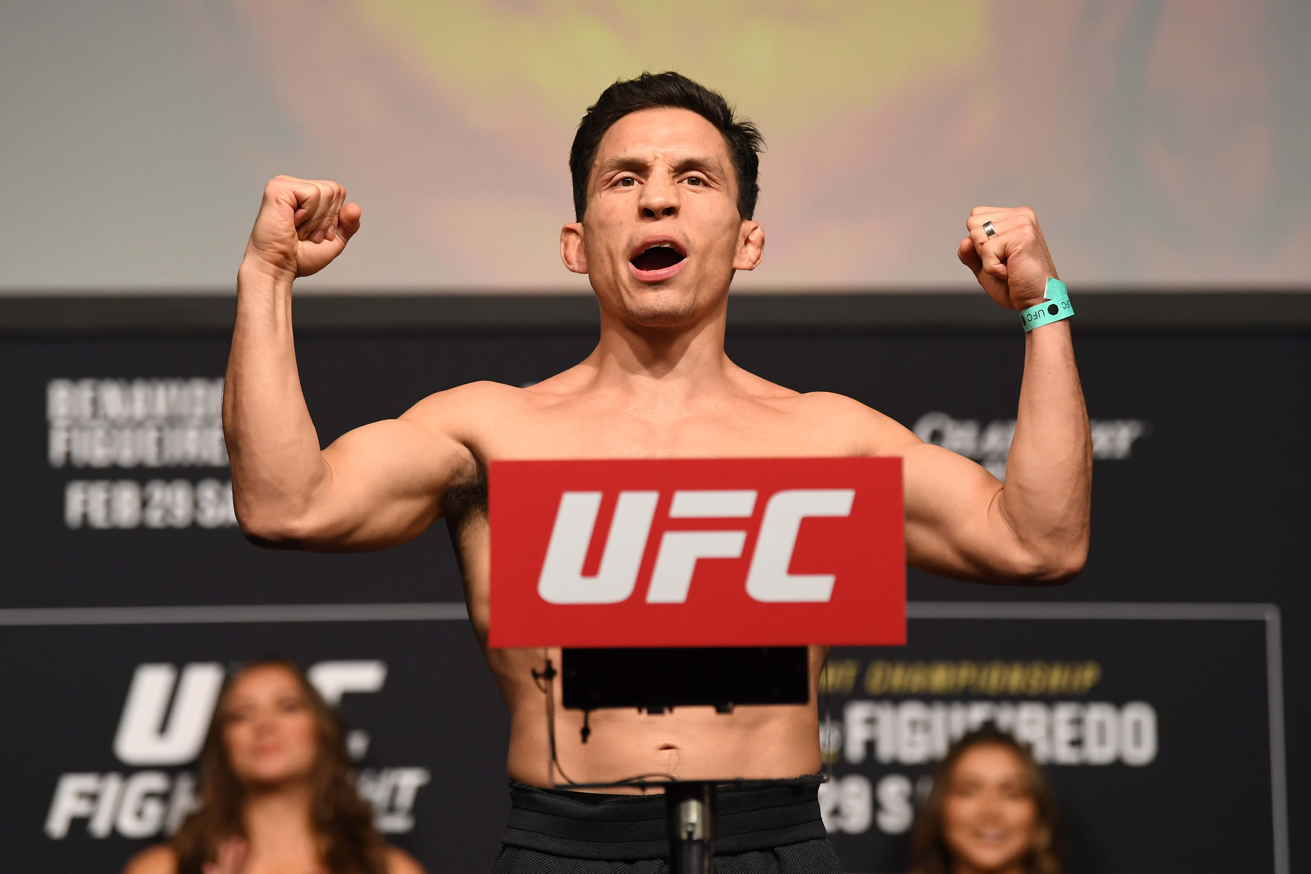 MMA 桌布 壁紙 — 一名肌肉發達的UFC拳擊手在體重磅上勝利地彎曲雙臂，胸前有紅色UFC標誌。