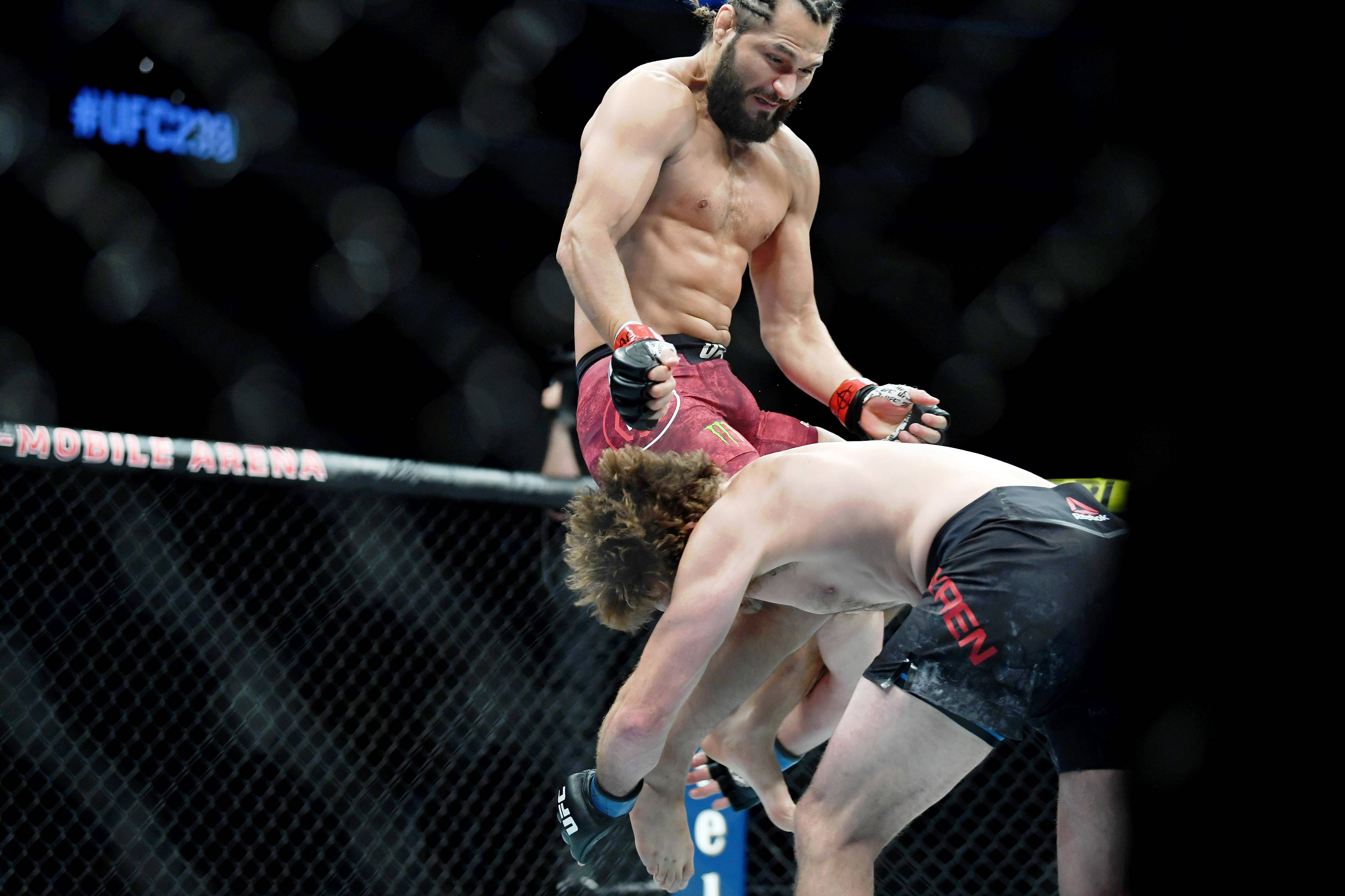 UFC 桌布 壁紙 — 一名肌肉發達的戰士穿著紅色短褲，在UFC八角籠中以強烈的專注力壓制對手。