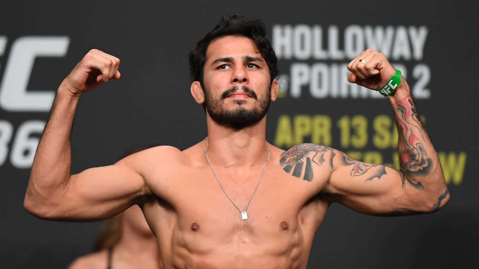 MMA 桌布 壁紙 — 一名肌肉發達的拳手在UFC賽事背景下彎曲雙臂，手臂和胸部上的刺青清晰可見。