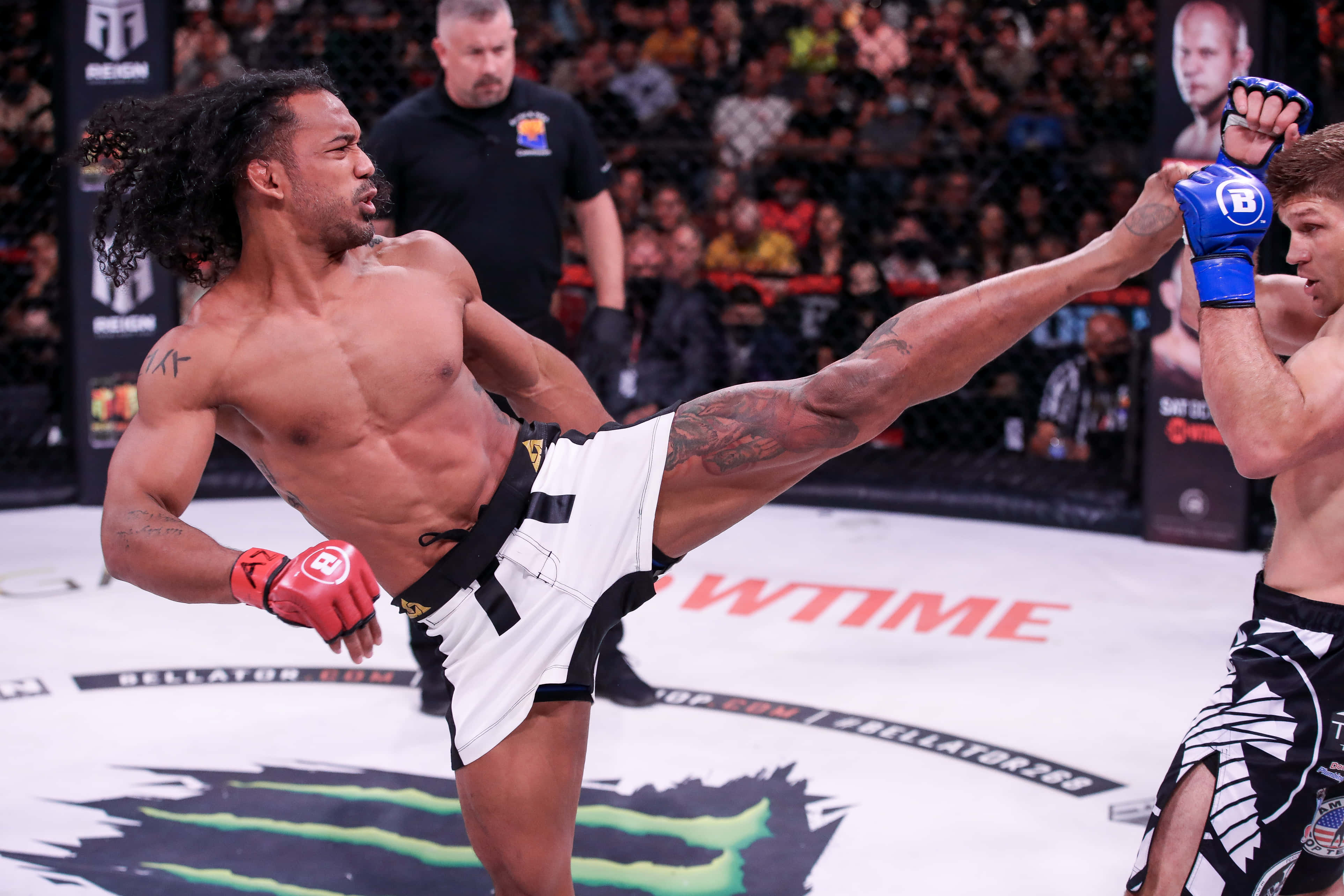 Fight 桌布 壁紙 — 一名肌肉發達的拳手在燈光明亮的MMA八角籠中使出高踢，背景是咆哮的人群。