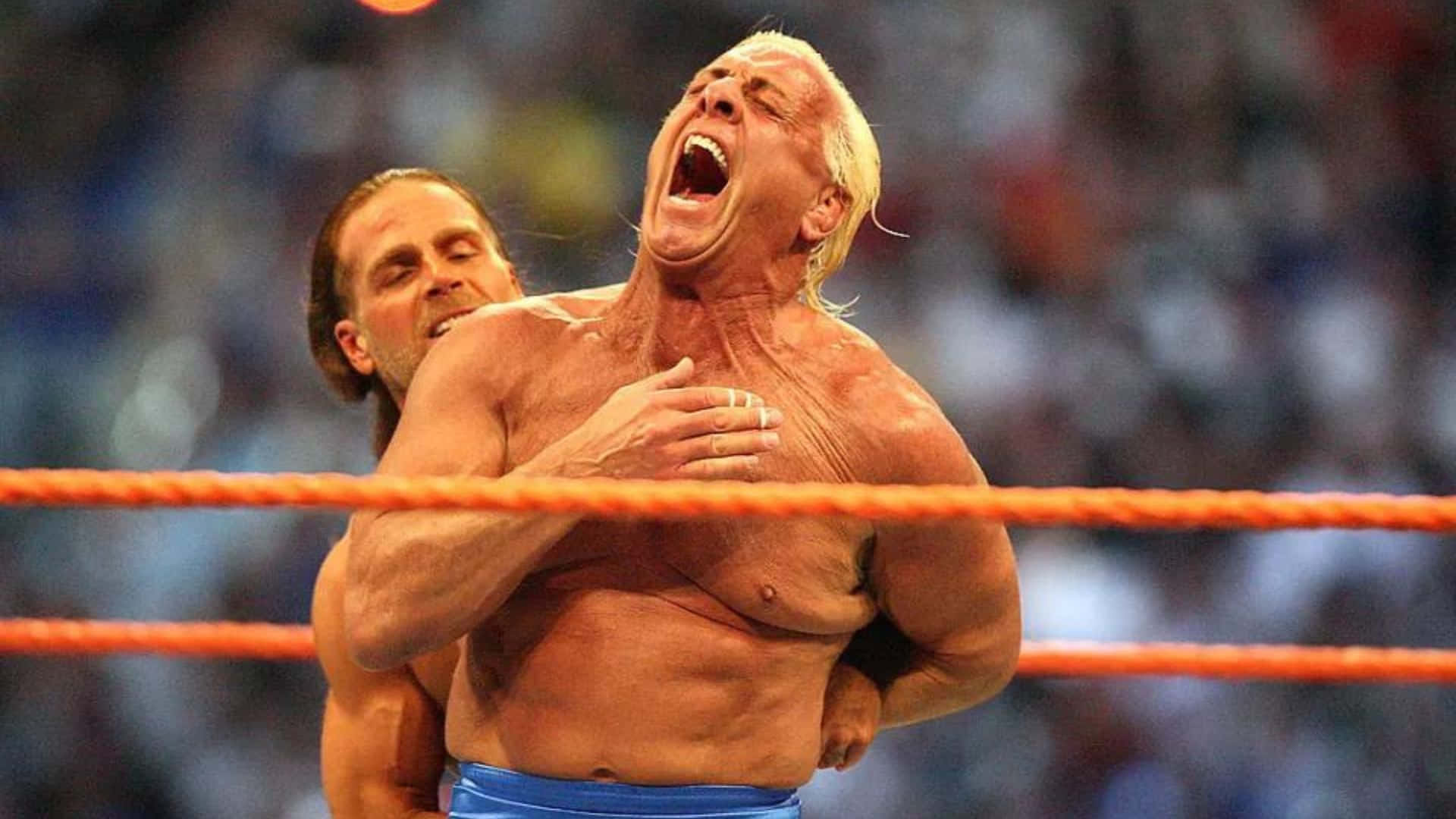 Wrestling 桌布 壁紙 — 一名肌肉發達的摔角手在明亮的橙色擂台上被對手鎖喉，痛苦地尖叫。