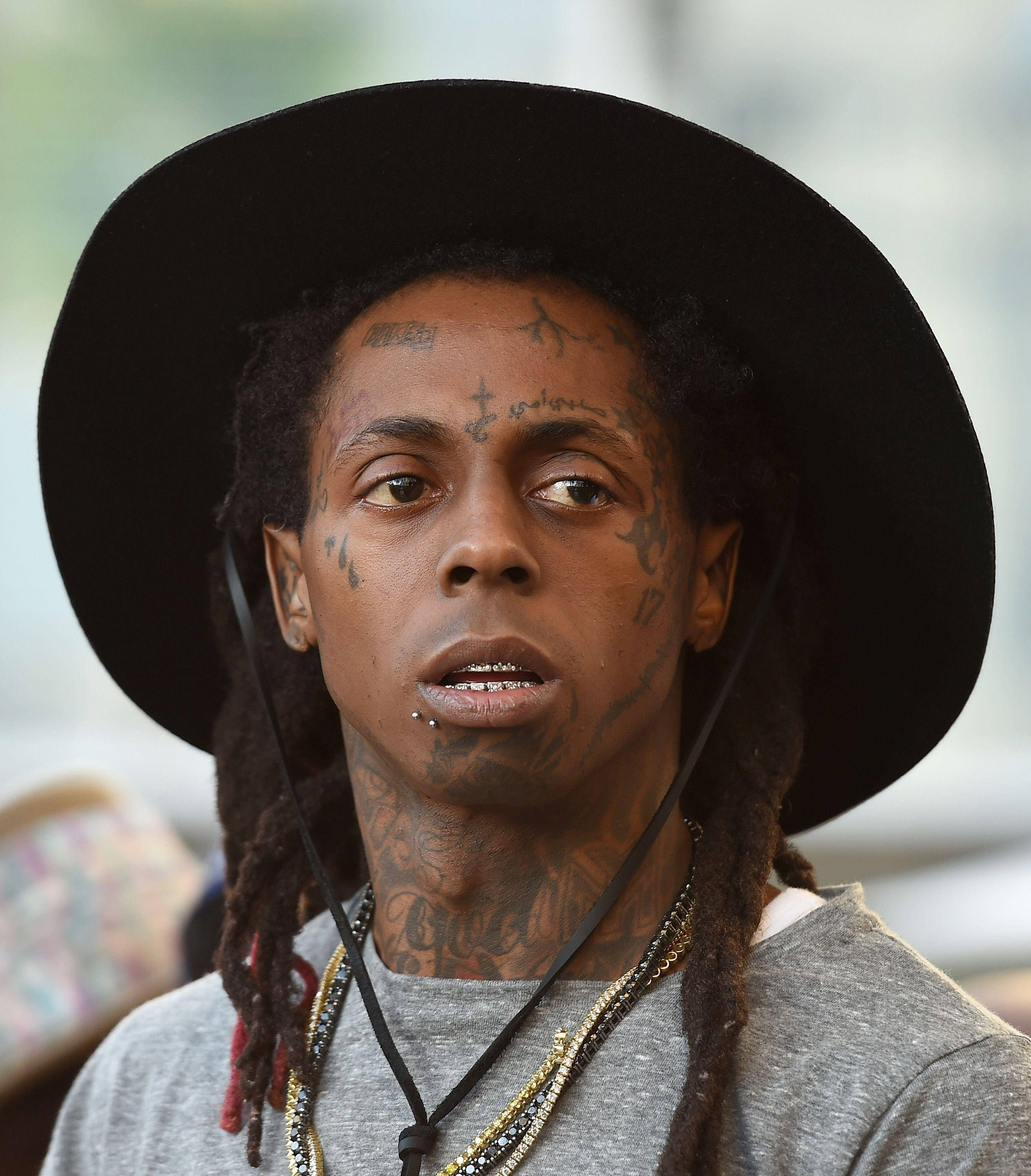 Lil Wayne 桌布 壁紙 — 一名臉上和頸部有刺青的男子，戴著黑色寬邊帽和層疊項鍊的特寫肖像。