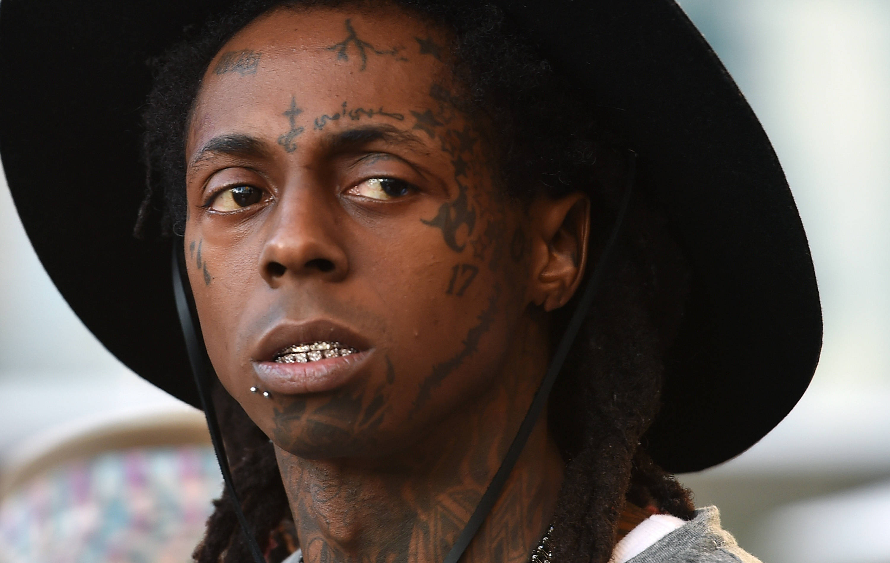 Lil Wayne 桌布 壁紙 — 一名臉上和頸部有刺青的男子戴著黑色寬邊帽的特寫肖像。