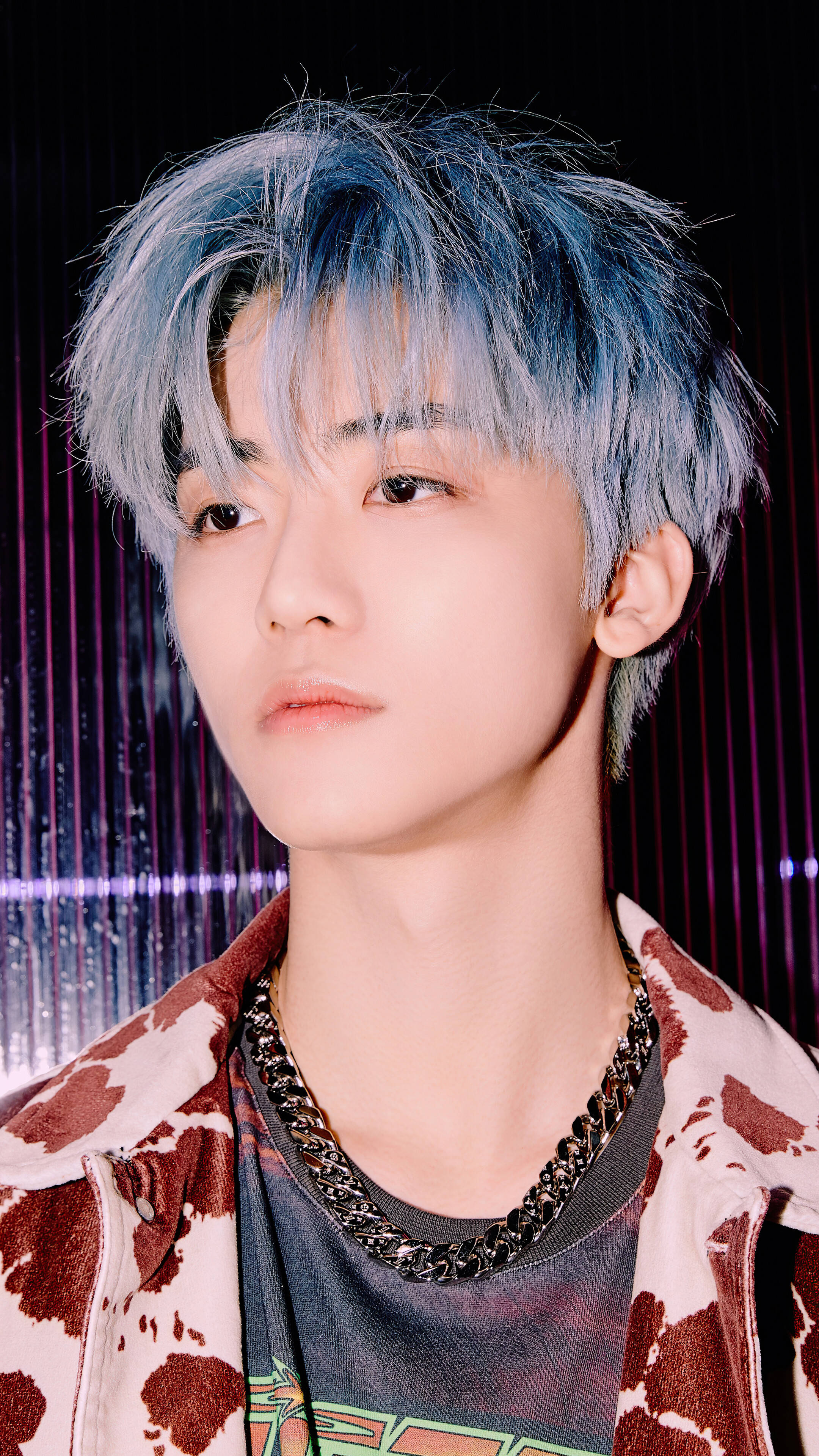 jaemin 桌布 壁紙 — 一名藍髮青年身穿乳牛印花外套，在發光的紫色窗簾背景下平靜地凝視。