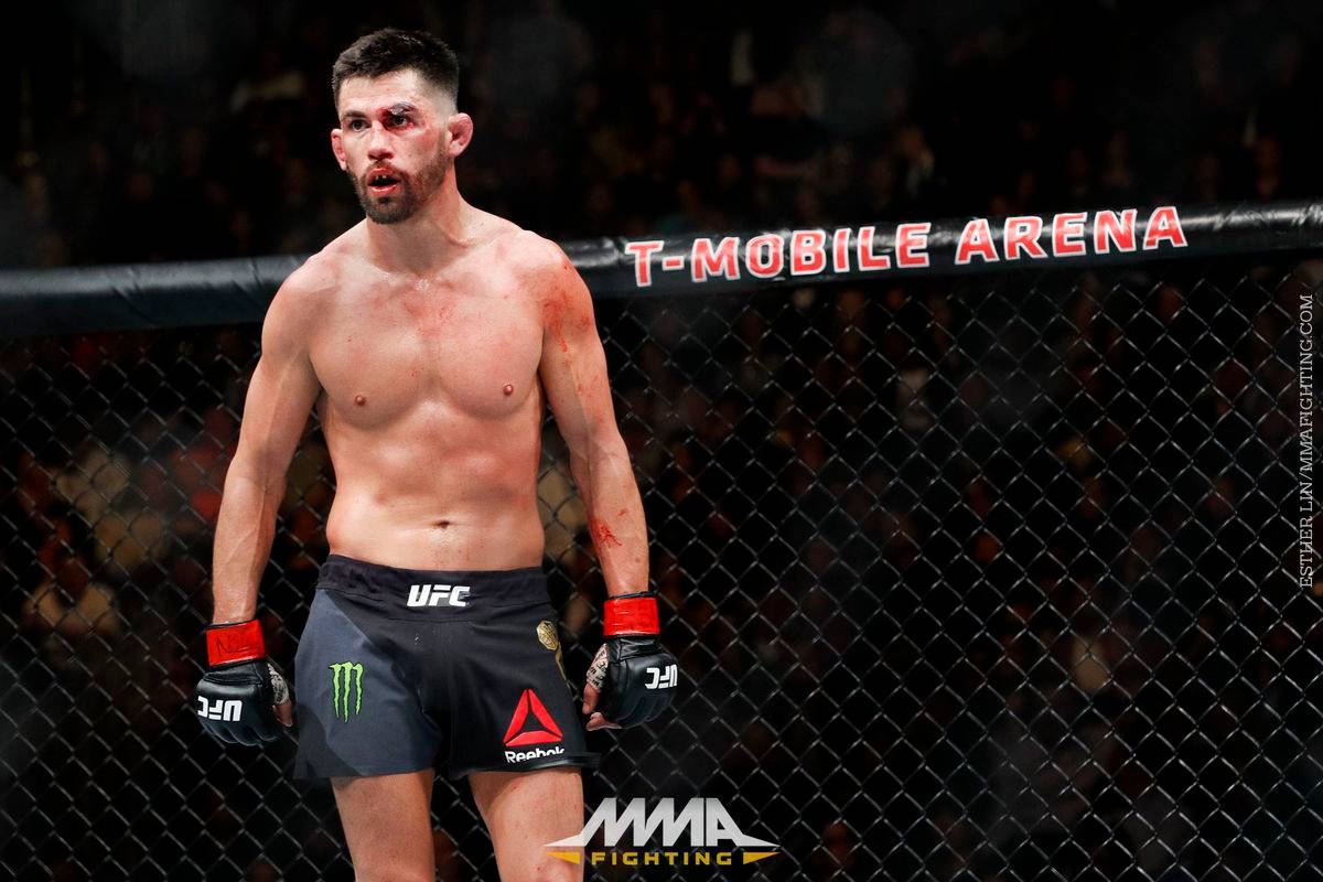 桌布 壁紙 — 一名血跡斑斑的MMA拳手在T-Mobile Arena的籠中，經過一場殘酷比賽後疲憊地站立。