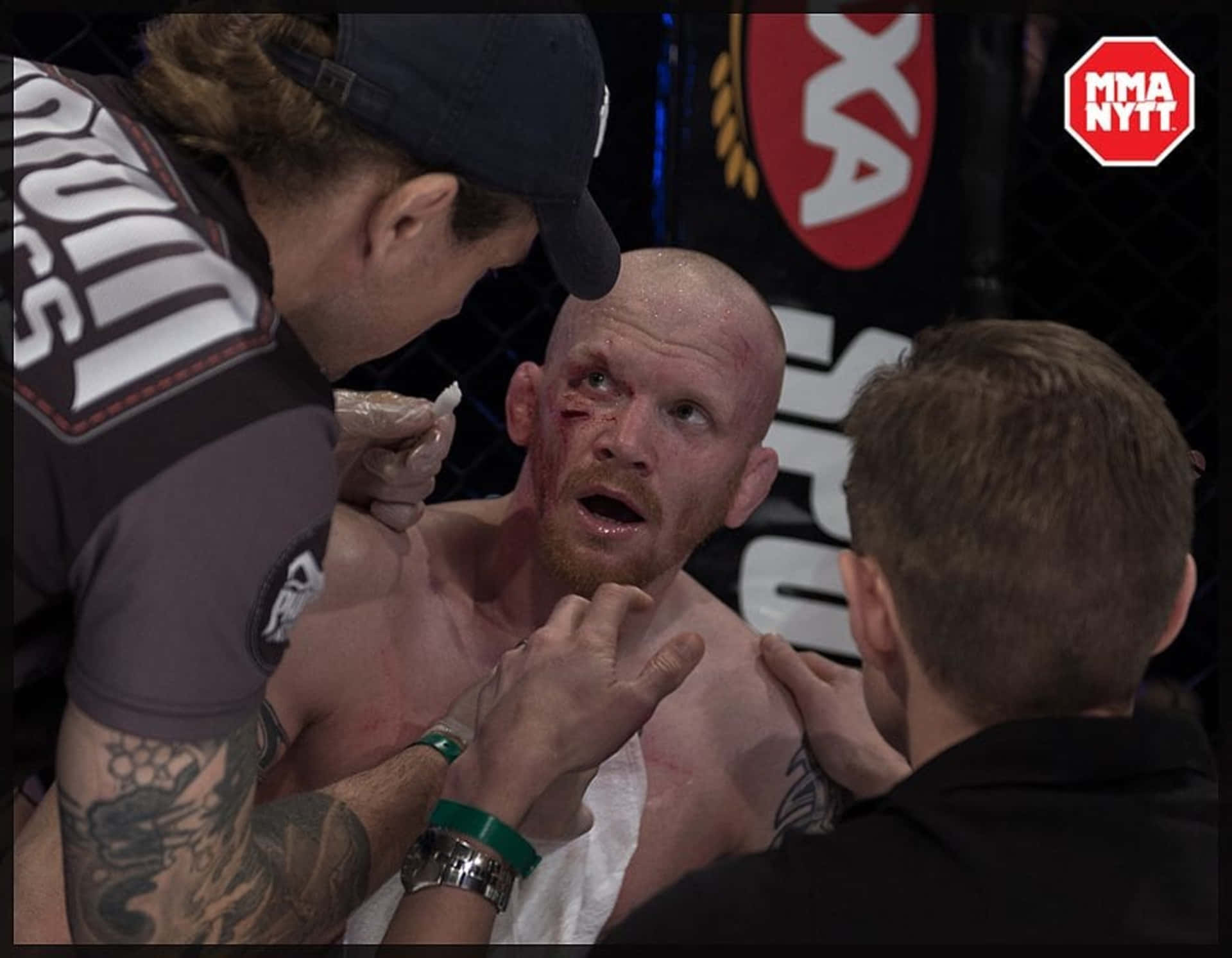 MMA 桌布 壁紙 — 一名血跡斑斑的MMA拳手在八角籠內，於一場殘酷比賽後接受醫護人員的照料。