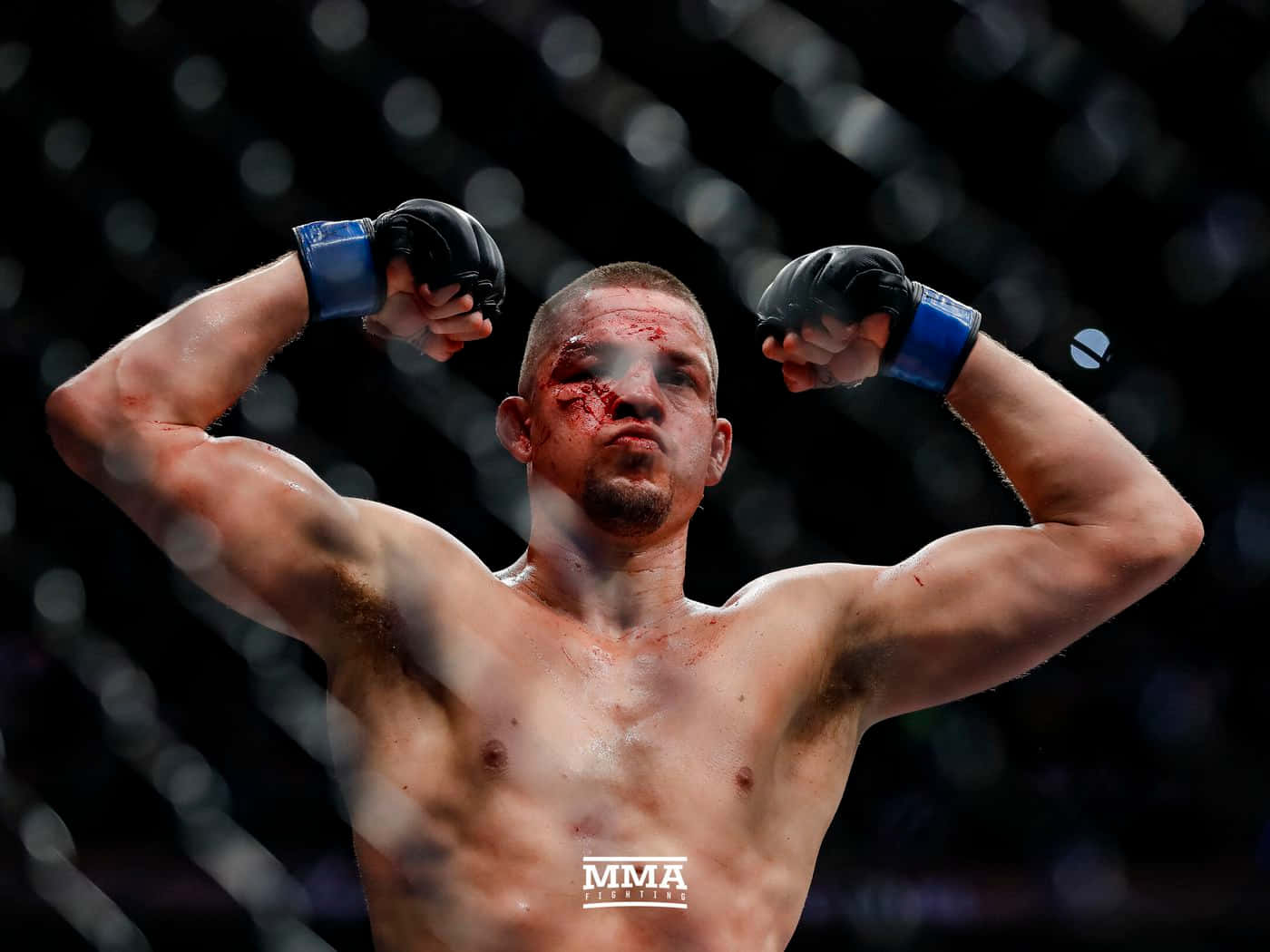UFC 桌布 壁紙 — 一名血跡斑斑的MMA拳手在明亮的場館燈光下，在八角籠內勝利地展示肌肉。