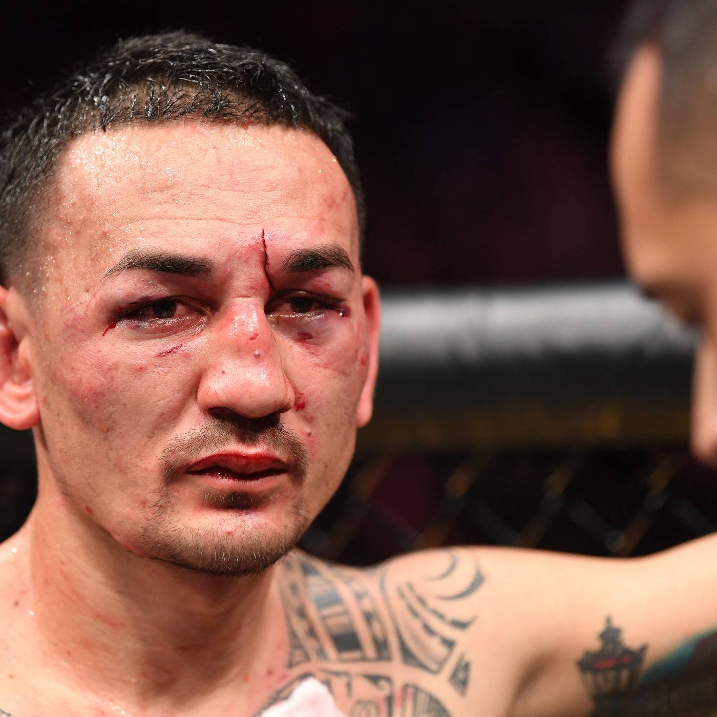 UFC 桌布 壁紙 — 一名血跡斑斑的戰士，眉毛裂開，在籠中激烈地盯著一場殘酷的MMA比賽。