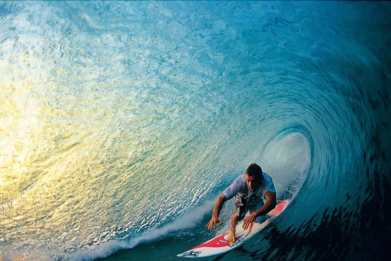 surfing 桌布 壁紙 — 一名衝浪手在巨大的碧藍色海浪中衝浪，金色的陽光在水面上反射。